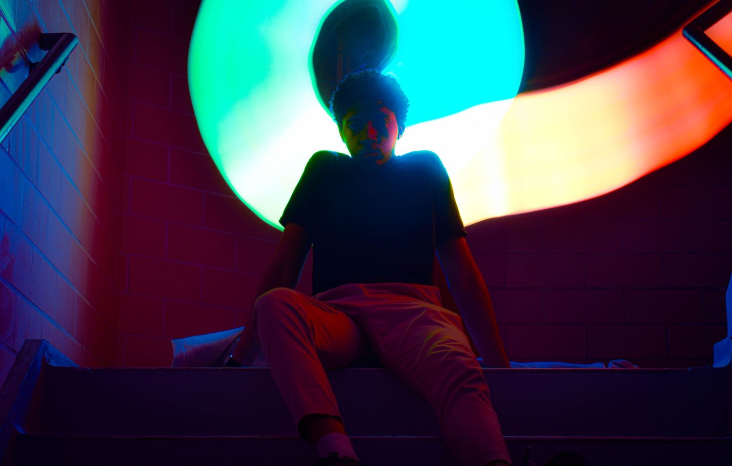 Colorful neon lights create abstract patterns and reflections in a dark environment.