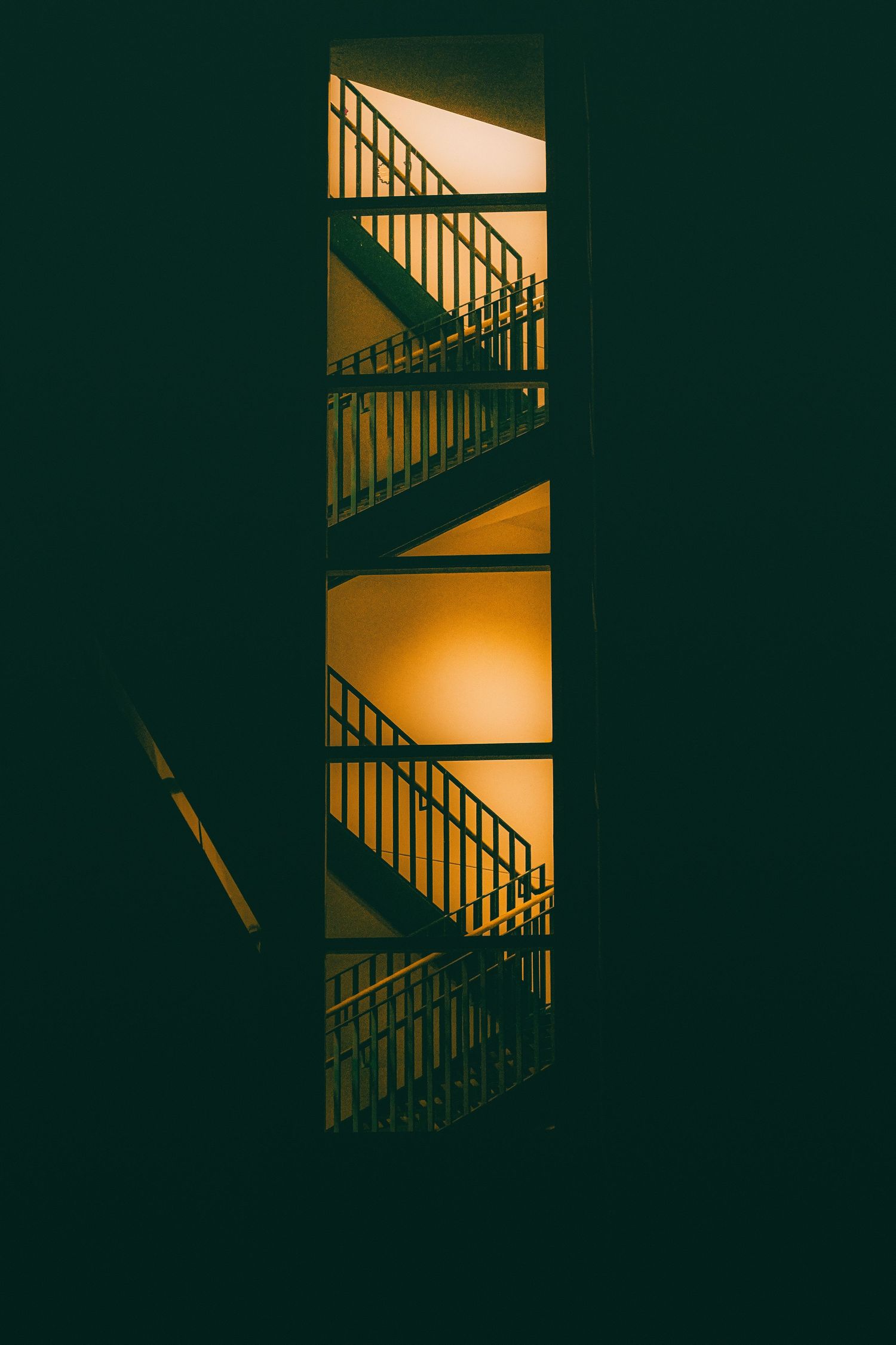 Moody stairwell with golden lighting casting geometric shadows.