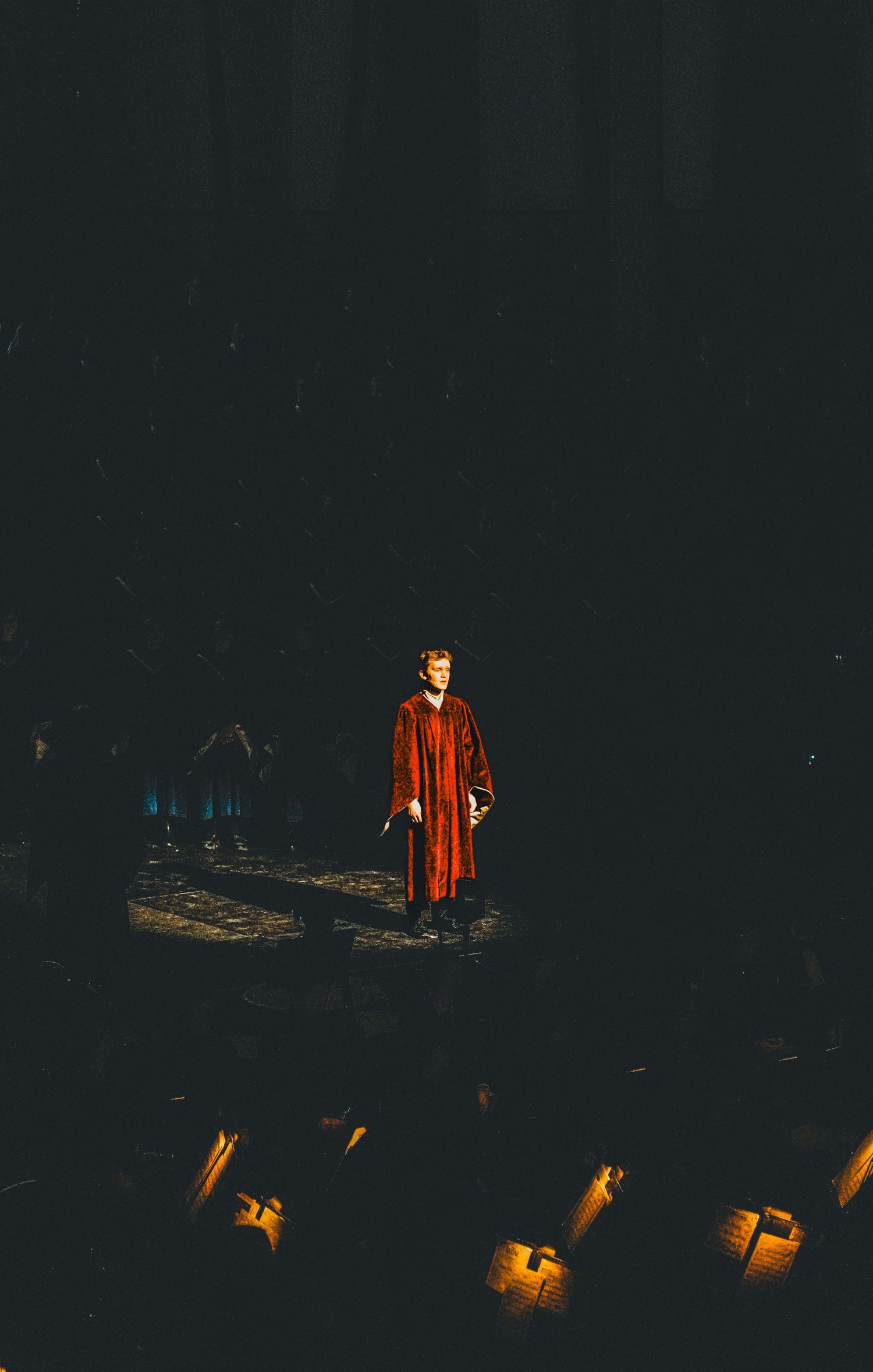 Stage performance with dramatic lighting and glowing lanterns in dark theater setting.
