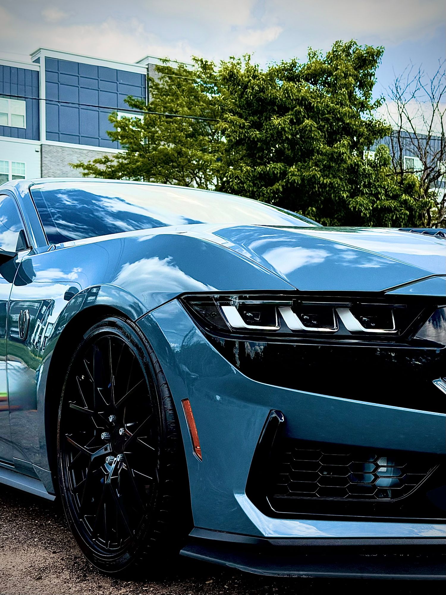 Blue Chevrolet Camaro sports car with black wheels parked outdoors, showcasing aggressive front fascia and sleek headlights.