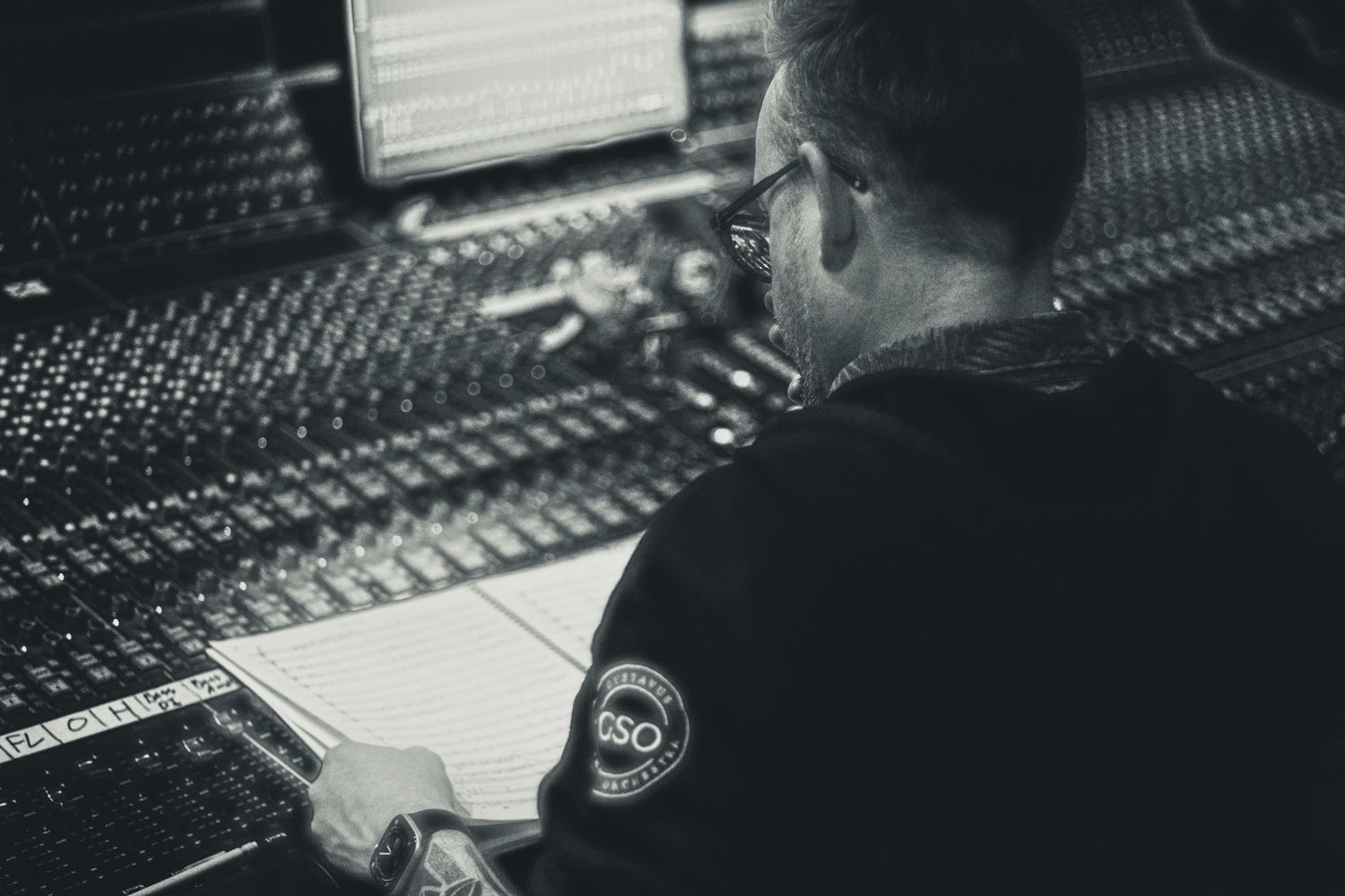 Music producer working at a large mixing console in a professional recording studio, black and white photo.
