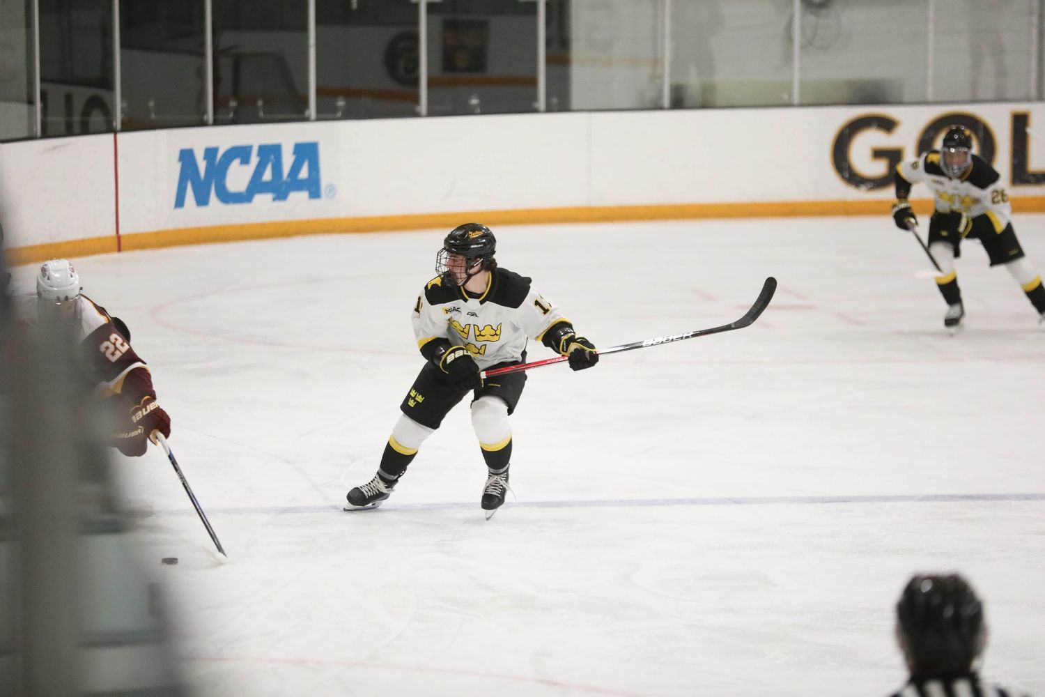 Hockey players in action on the ice with NCAA branding visible in the background.