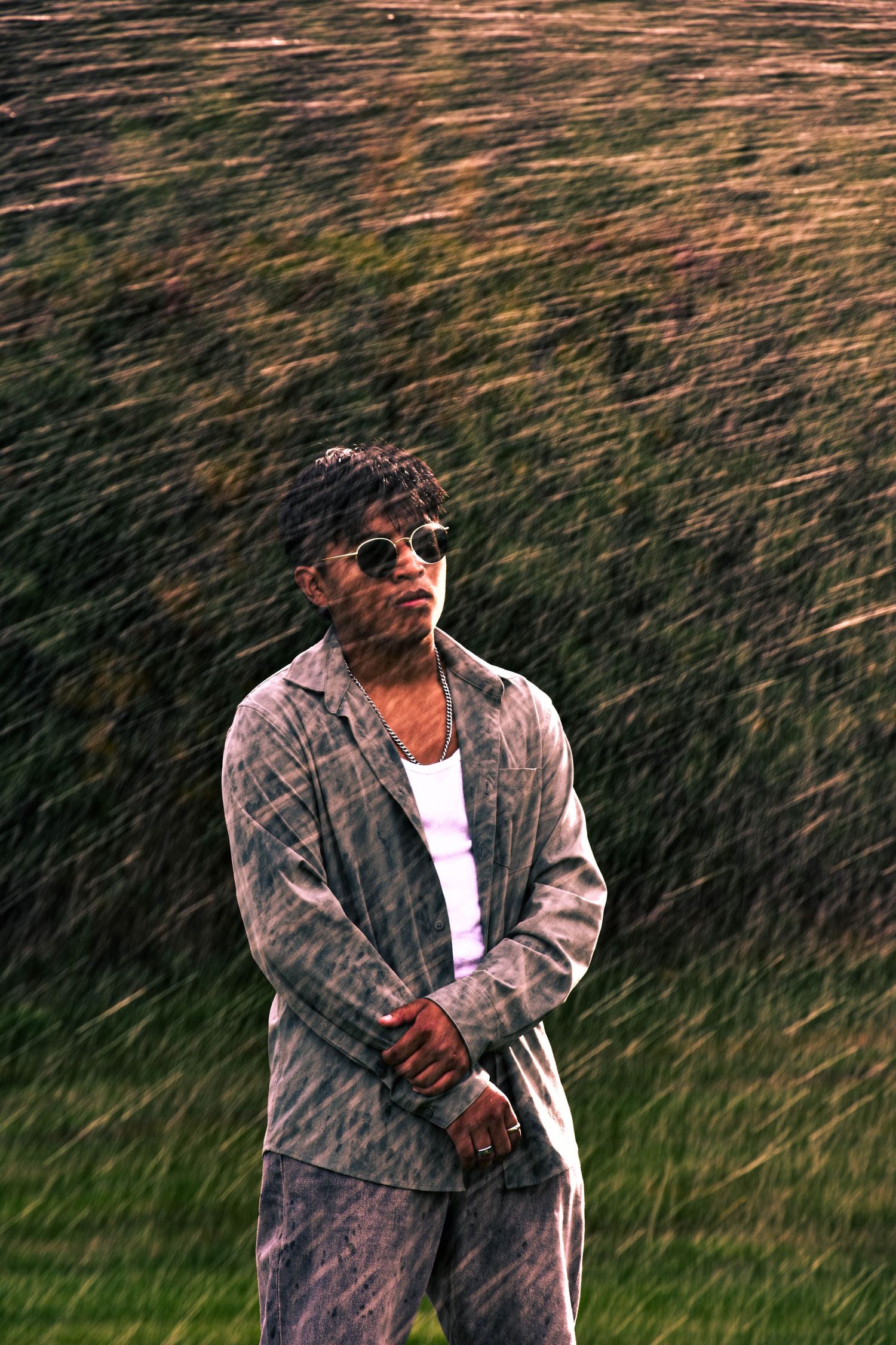 Artistic motion blur portrait of someone in plaid jacket against natural outdoor background with sprinklers.