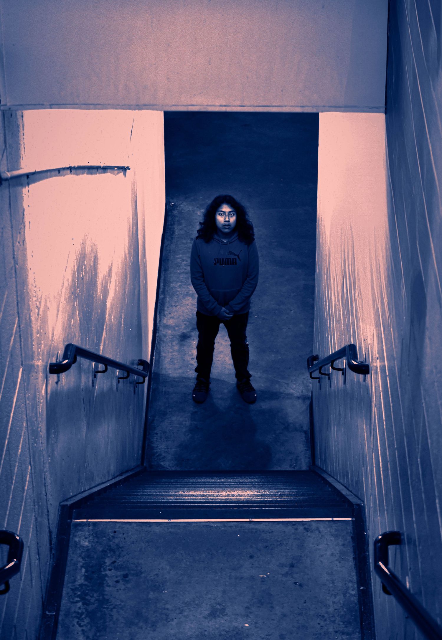 Eerie blue-tinted staircase with mysterious figures in the shadows.