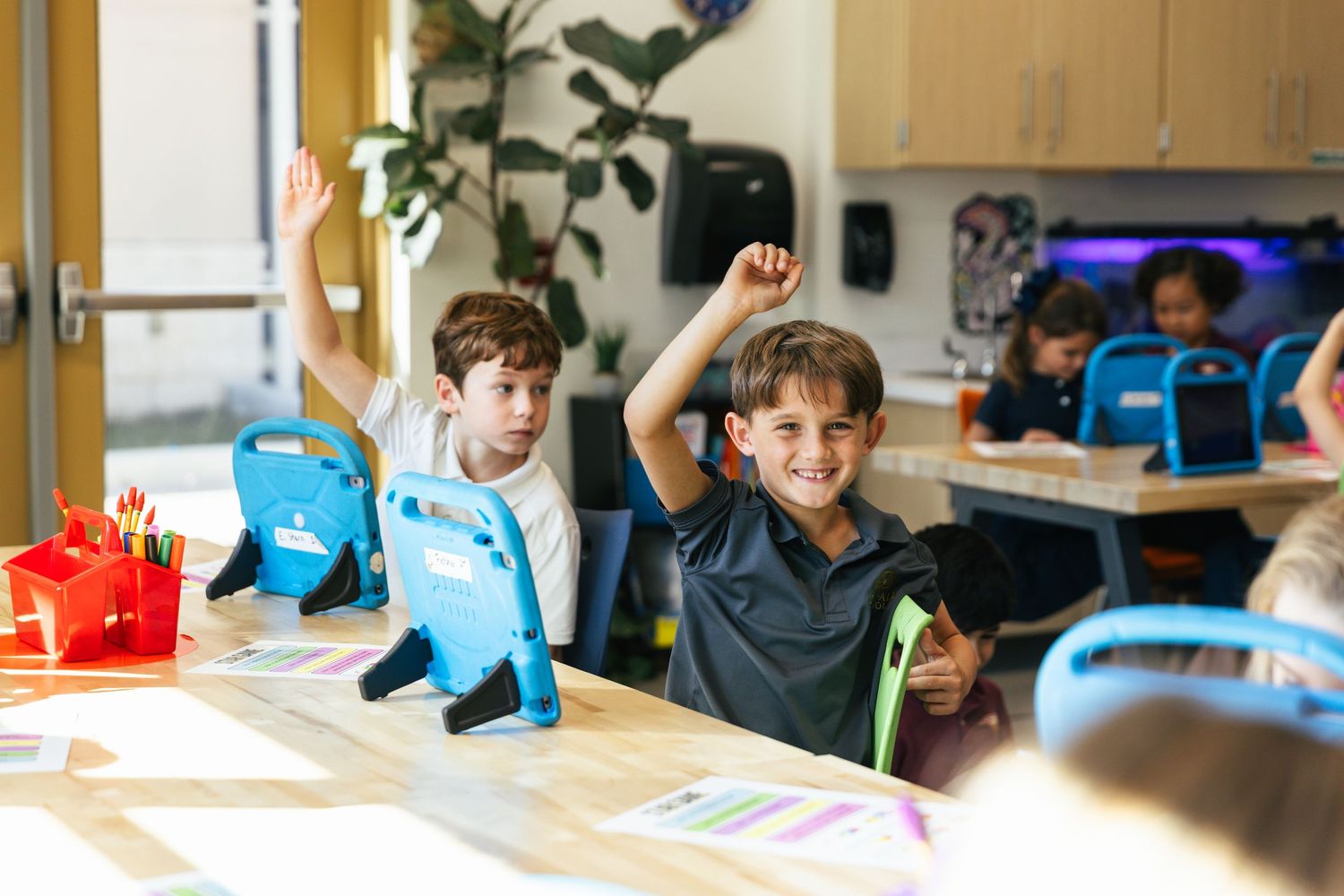 Young boy raising his hand in a classroom setting