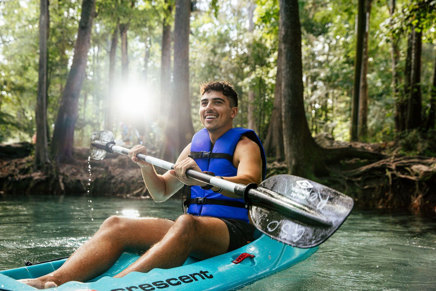 Young man sitting in a blue kayak smiling