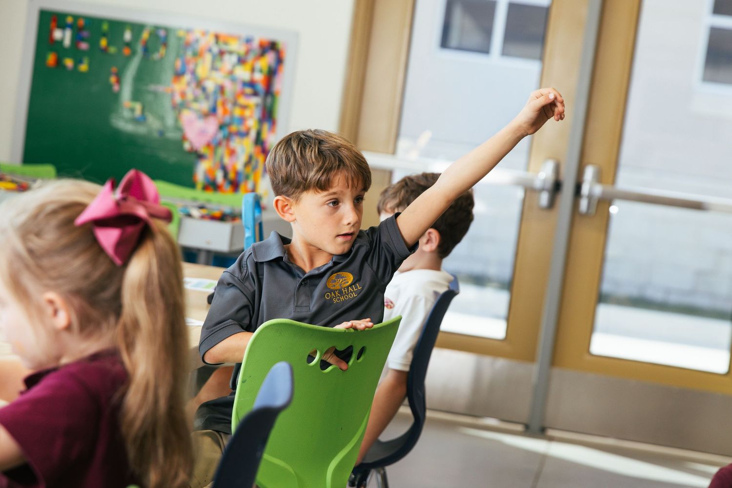 Young boy raising his hand in a classroom setting