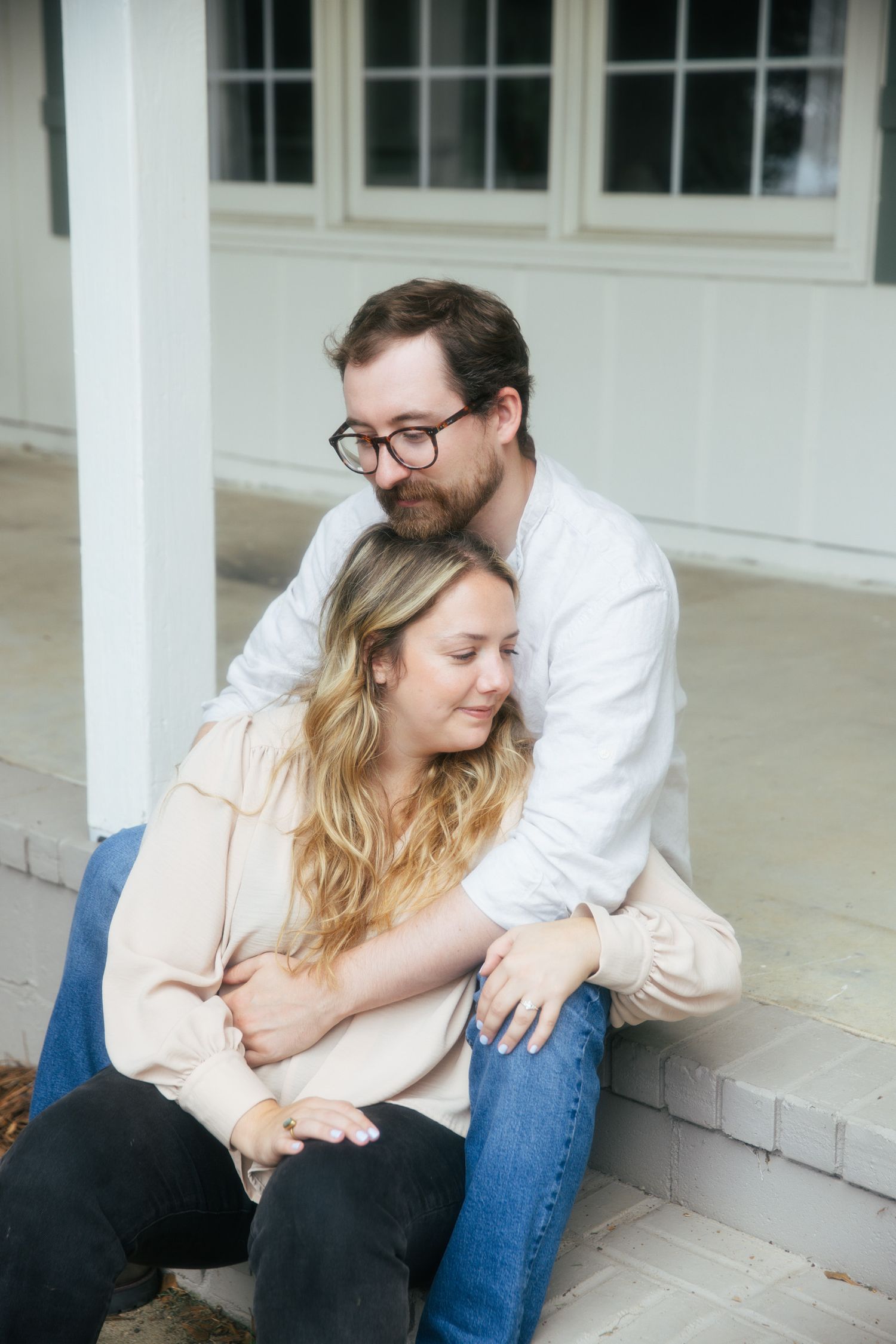 Young couple sitting together outside of a home snuggling