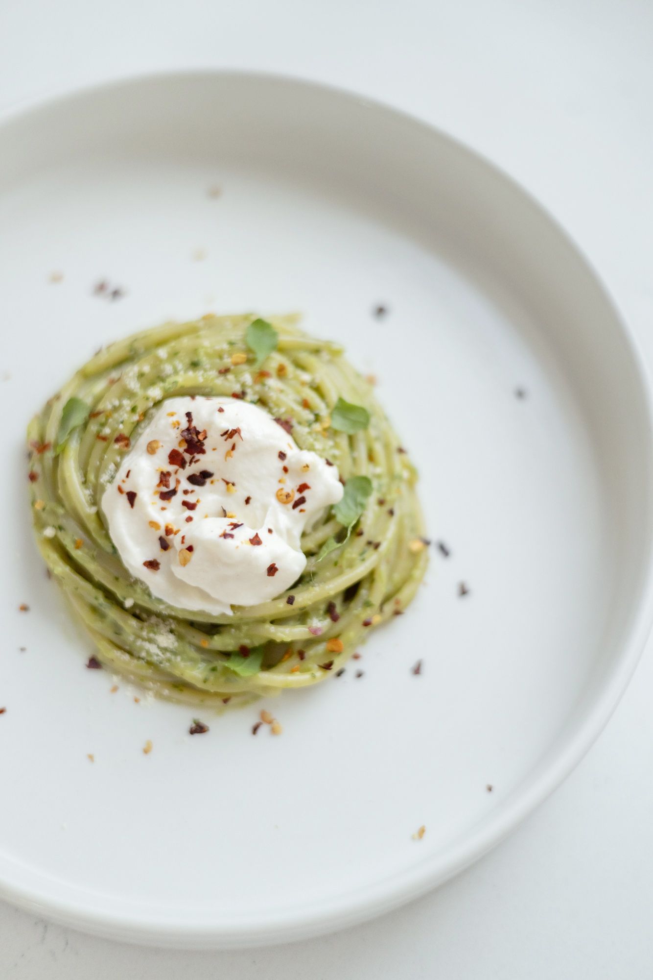 Green pasta on a white plate and background