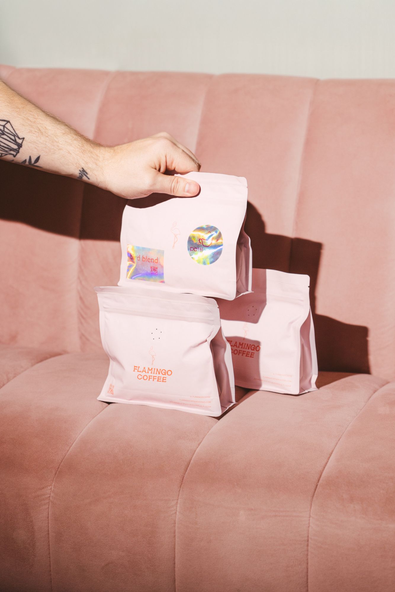 hand holding a bag of coffee on a pink background