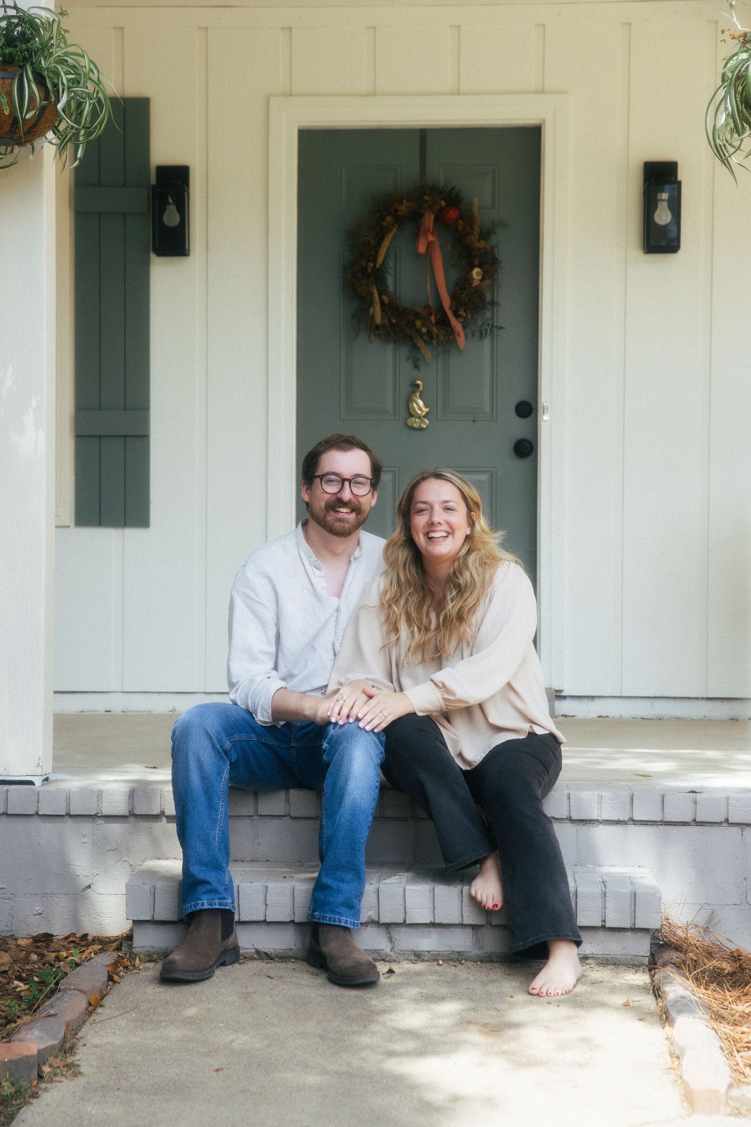 Young couple sitting together outside of a home smiling