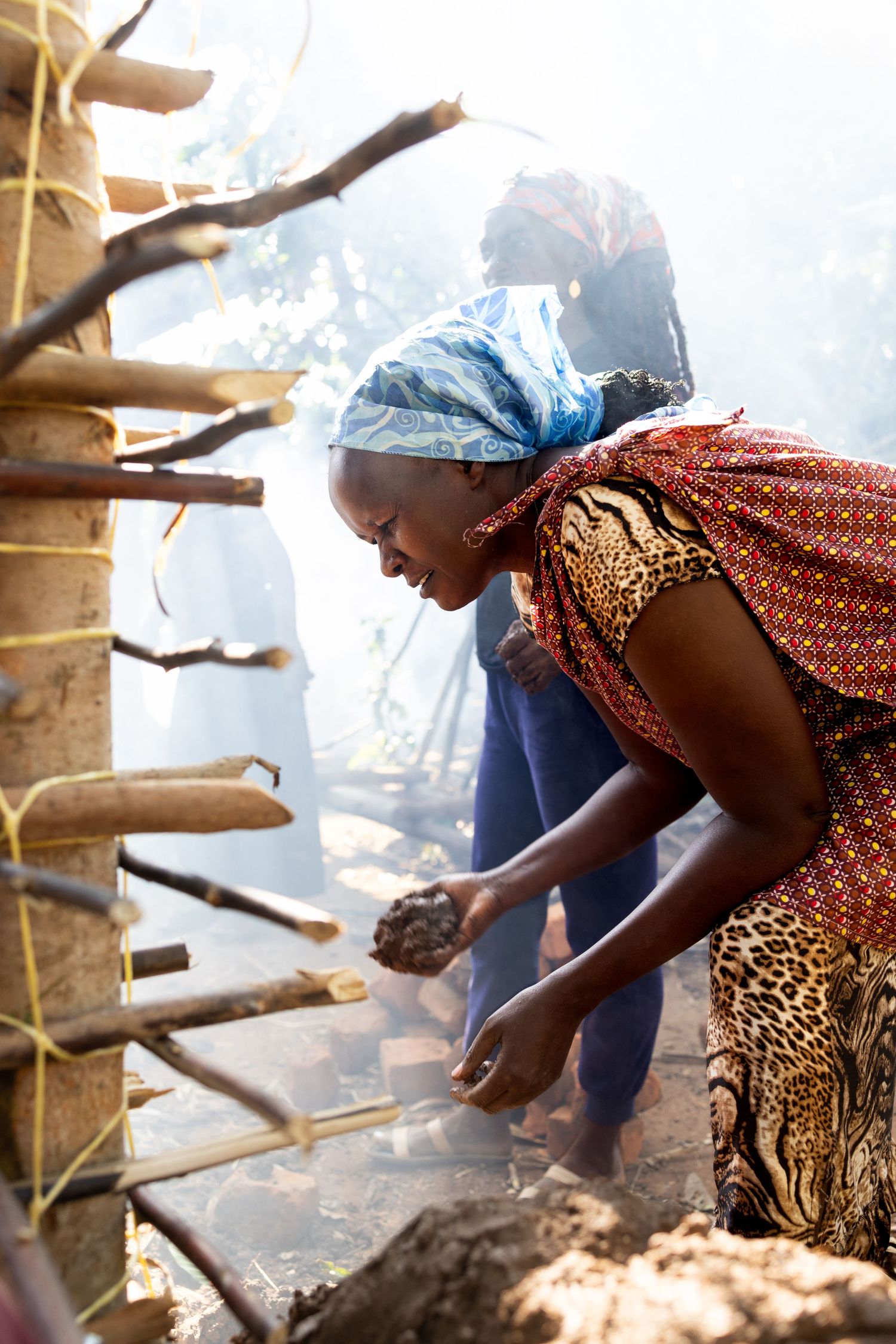 Woman holding mud outside of a hut
