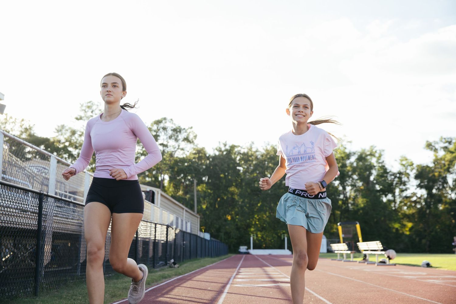 Two girls running on a track outside