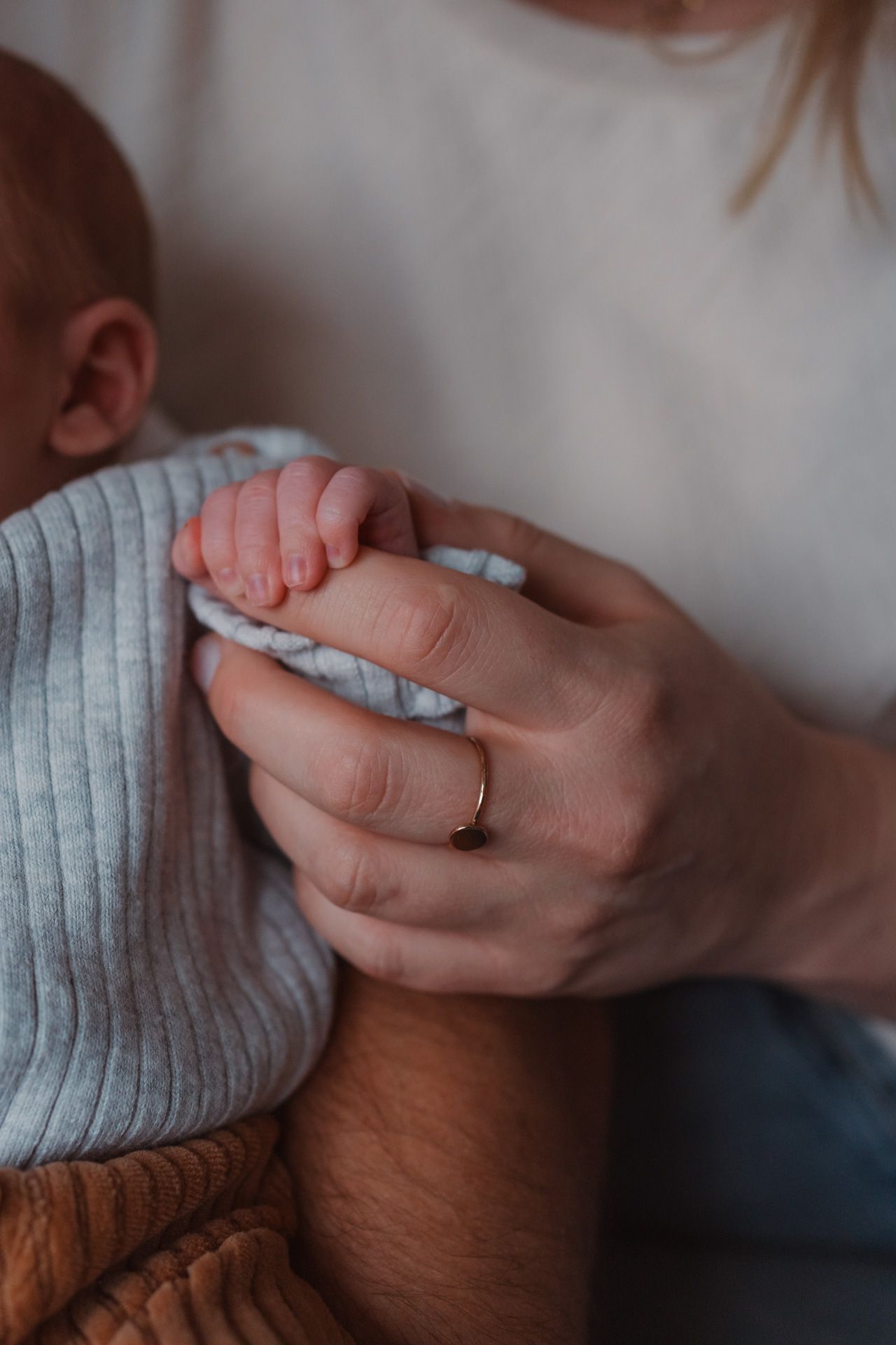 Handje van een pasgeboren baby tijdens een newbornshoot bij de ouders thuis.