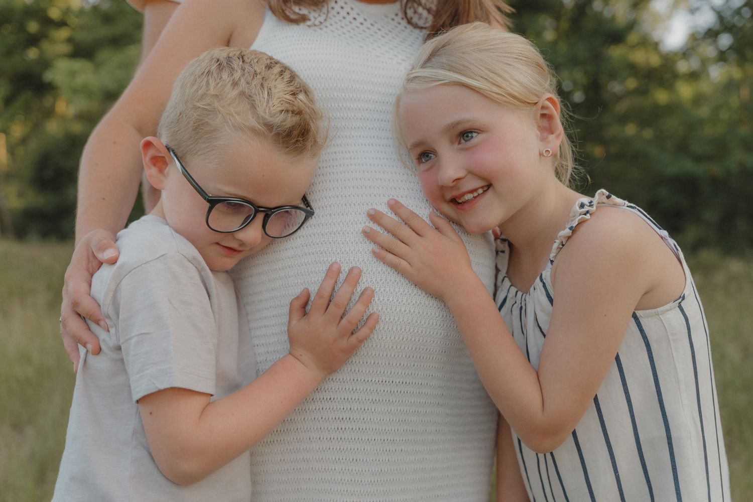 Dochter en zoon samen bij de zwangere buik van mama tijdens een zwangerschapsshoot.