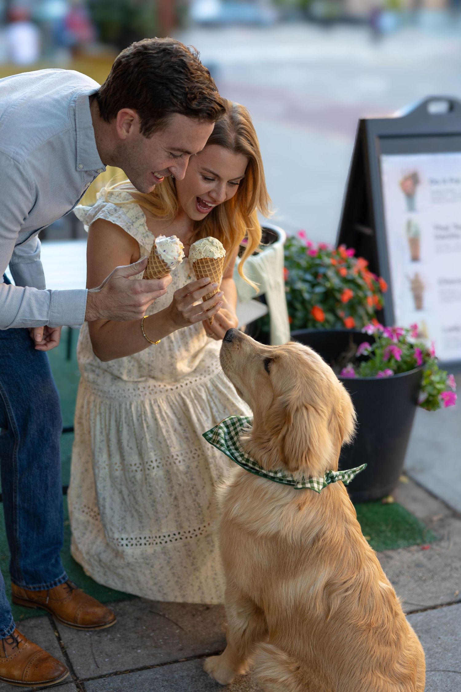 Engaged couple enjoy ice cream with their golden retriever puppy in Hoboken, New Jersey.