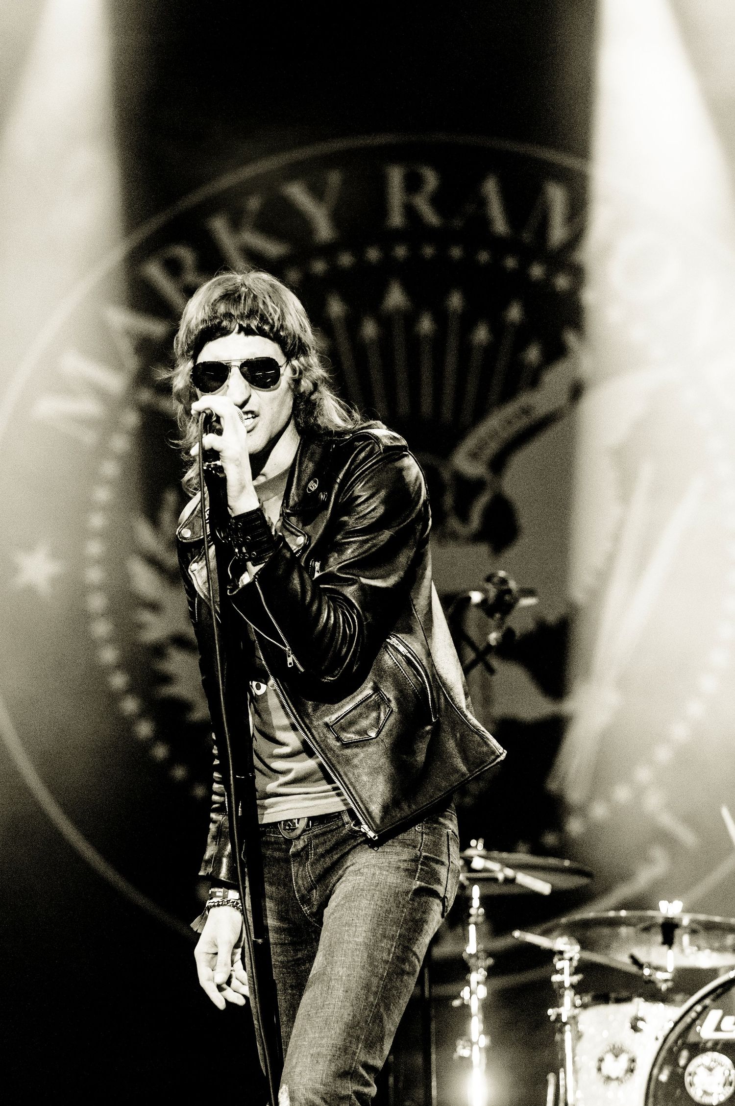 Performer in leather jacket and sunglasses singing on stage with vintage-style monochrome lighting.event photographer in guelph ontario