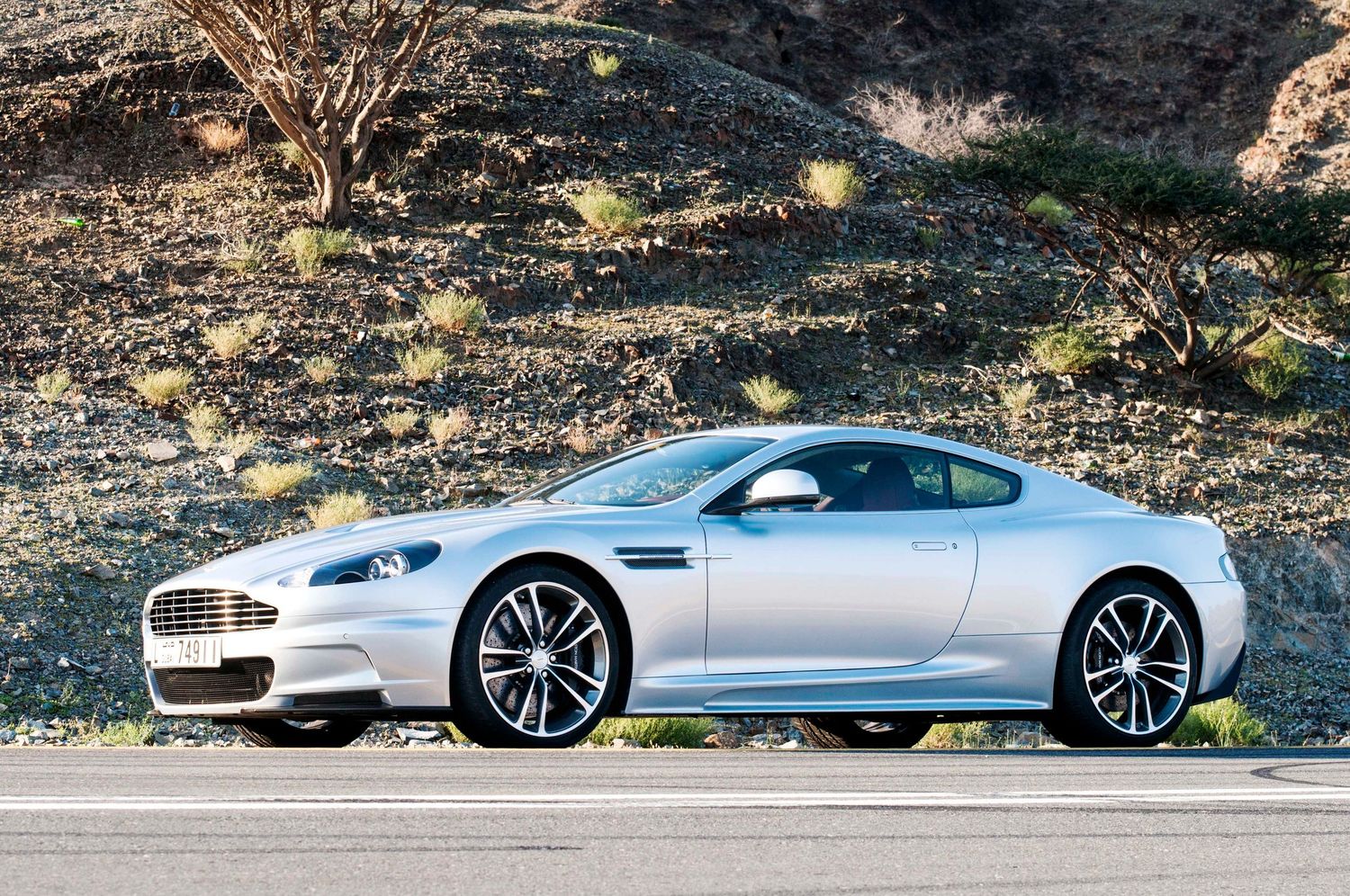 Silver luxury sports cars lined up along a scenic mountain road. car photography in ontario Aston Martin DBS