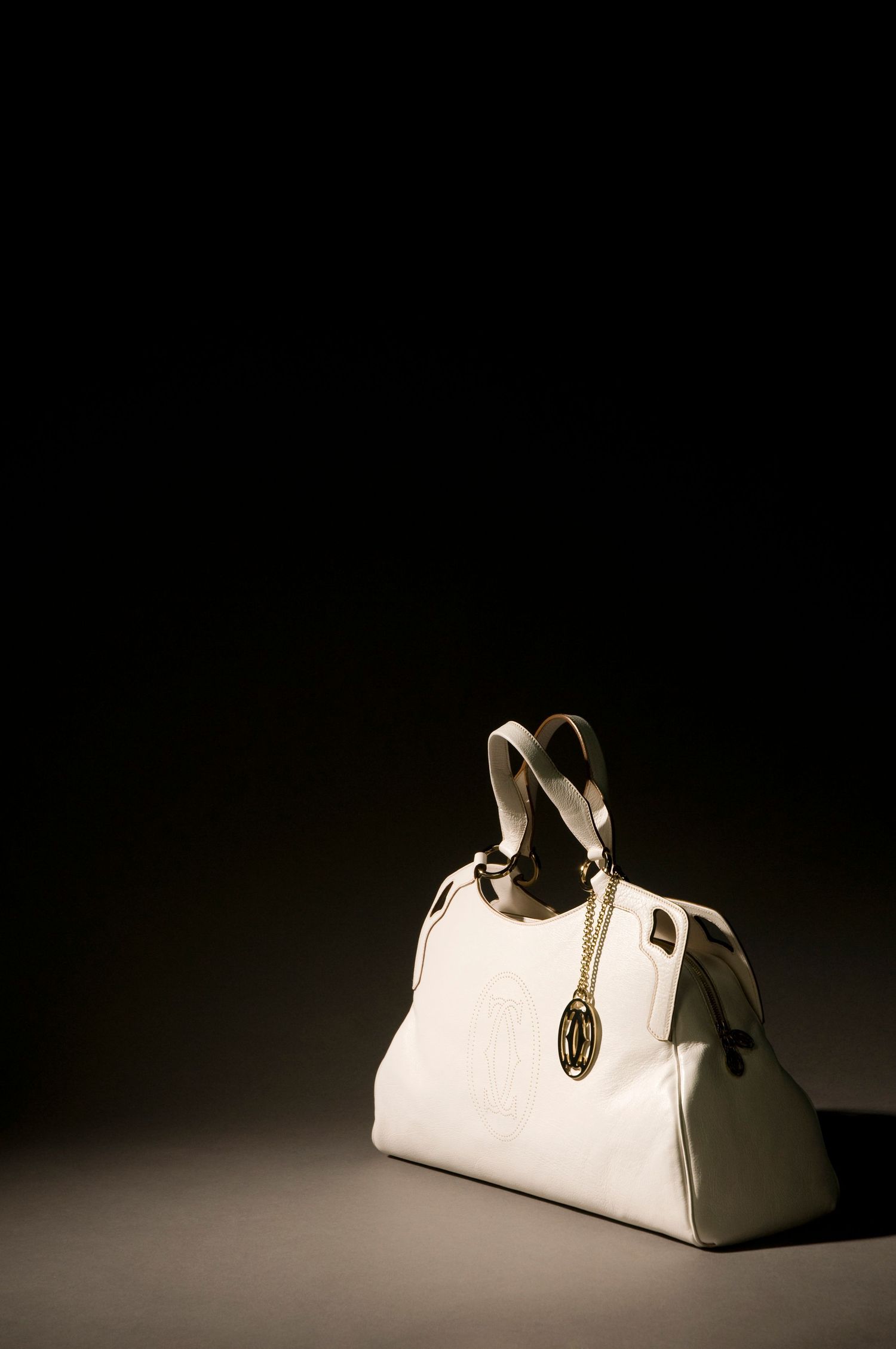 Elegant white leather handbag photographed in dramatic studio lighting against a dark background. Product Photography in Ontario