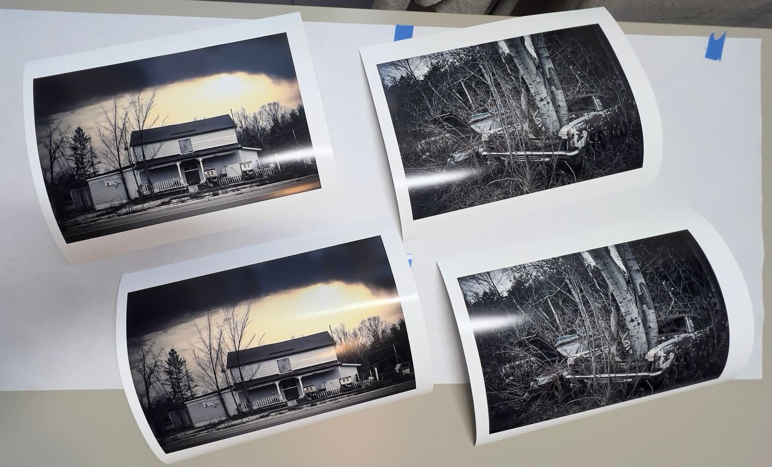 Multiple black and white photographic prints arranged on a light surface.