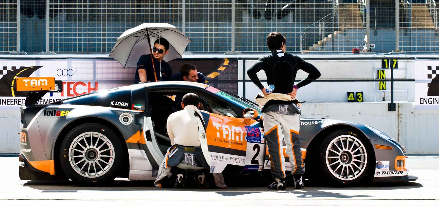 Racing cars lined up in pit lane with crew members performing maintenance. car photography in ontario