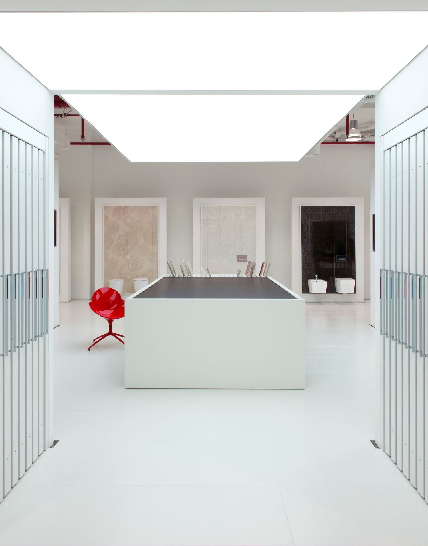 Minimalist white interior hallway with glass panels and red accent pieces. Commercial Interiors Photographer in Guelph Ontario