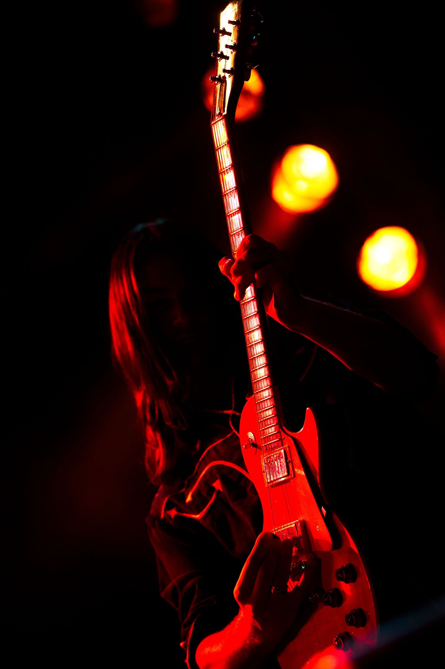 Electric guitar player performing on stage bathed in dramatic red lighting.Event photographer in Ontario Canada