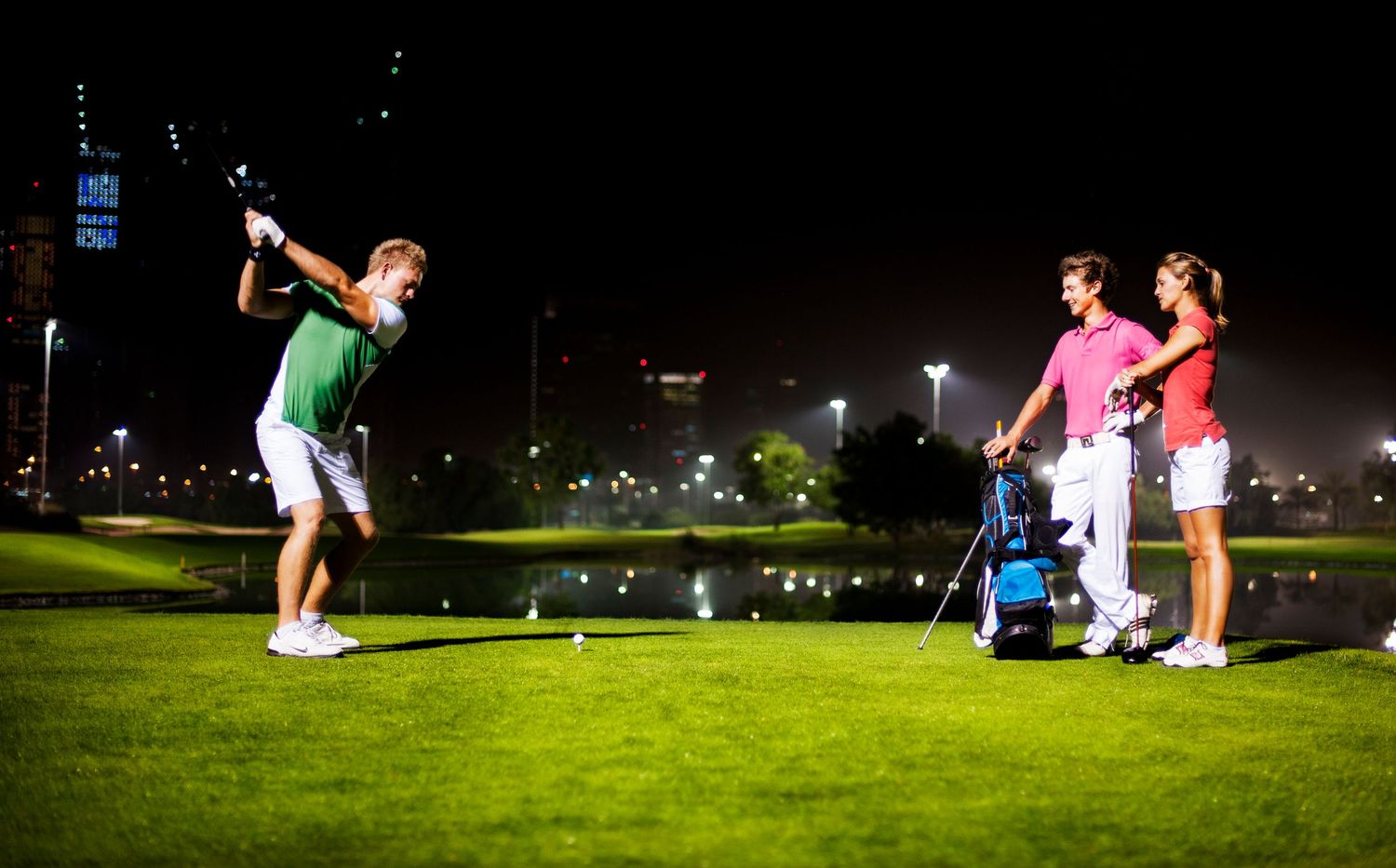 Night scene at golf driving range with players practicing under illuminated cityscape. Commercial Photographer in Guelph Ontario
