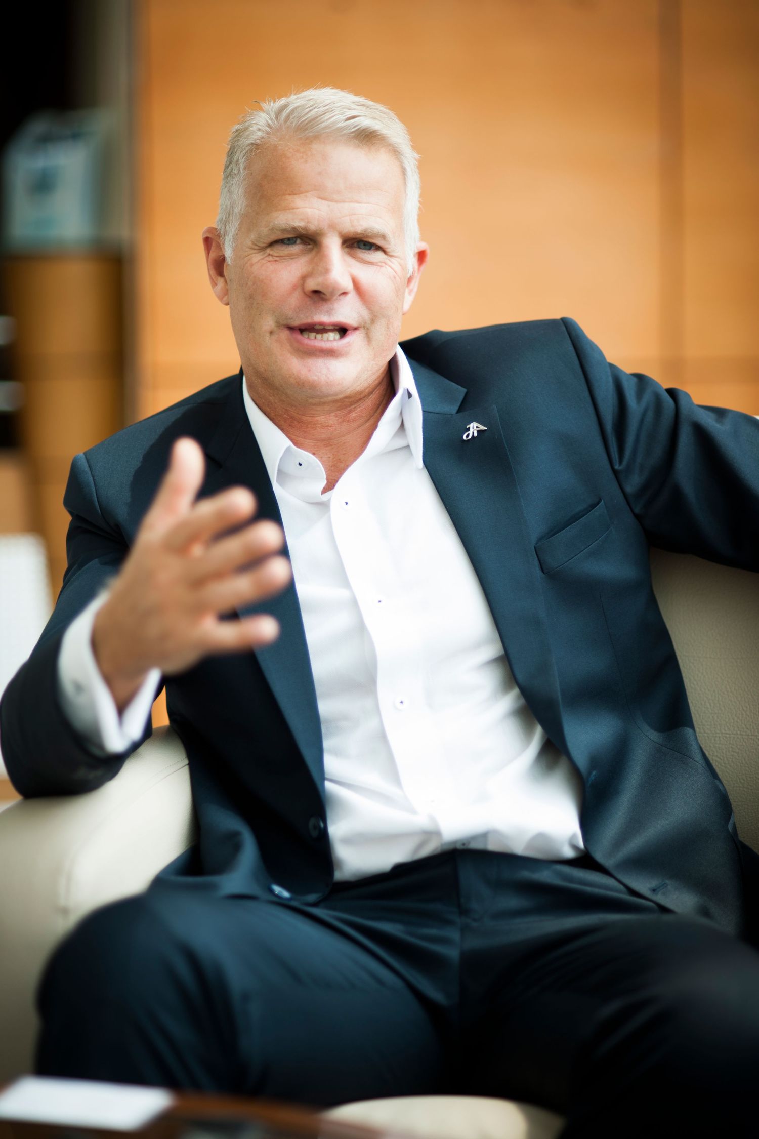 Executive in business attire gesturing while speaking during casual conversation.
