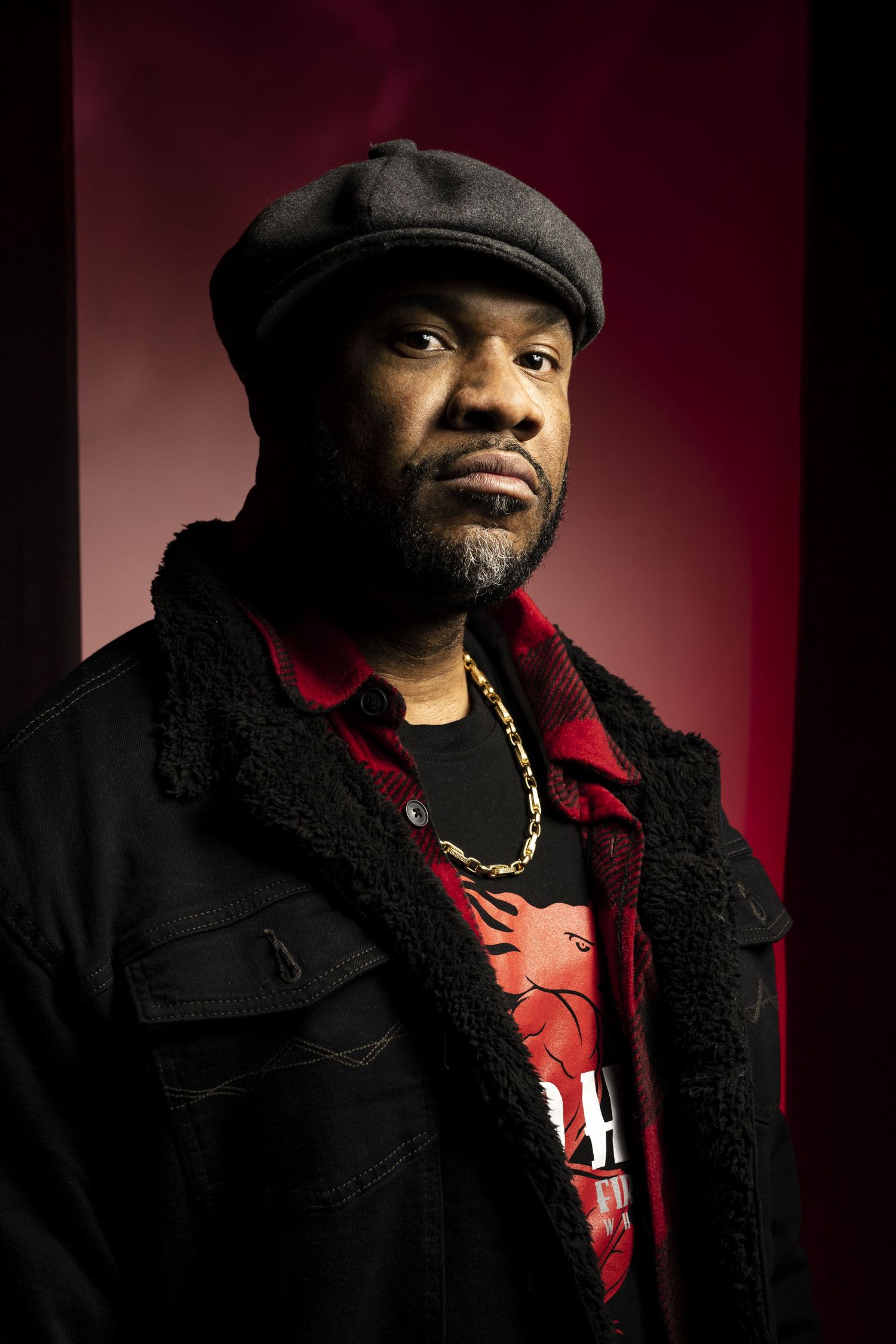 Studio portrait series of person in black coat and cap against dark red background. Commercial Photographer in Guelph and surrounding areas