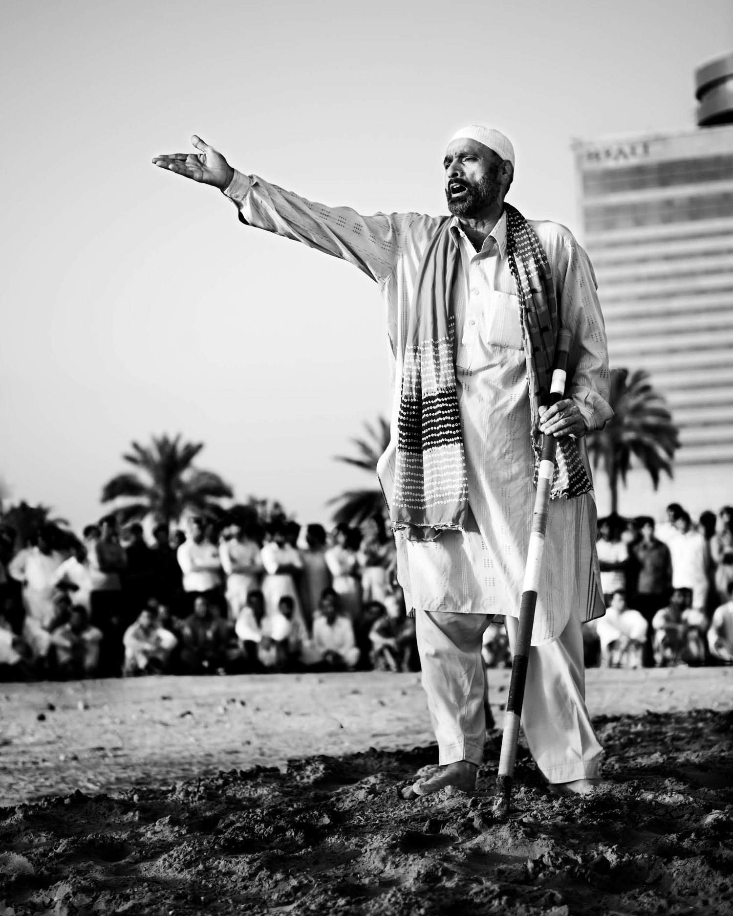 Black and white photograph of people gesturing in traditional Middle Eastern clothing outdoors. Dubai UAE