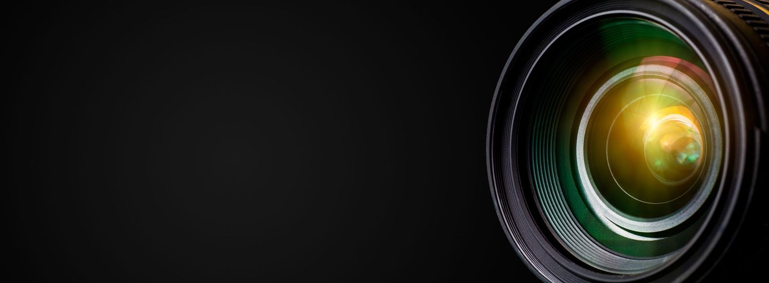 Close-up of camera lens elements with green and yellow reflections.