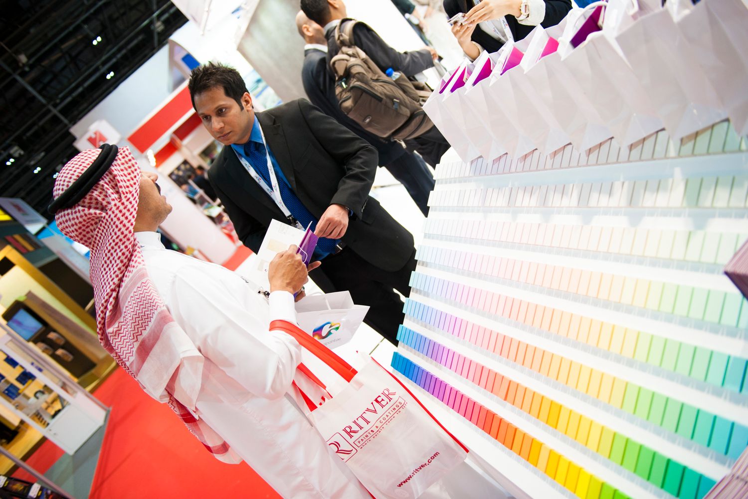 People examining colorful paint swatches and samples in a bright workspace.