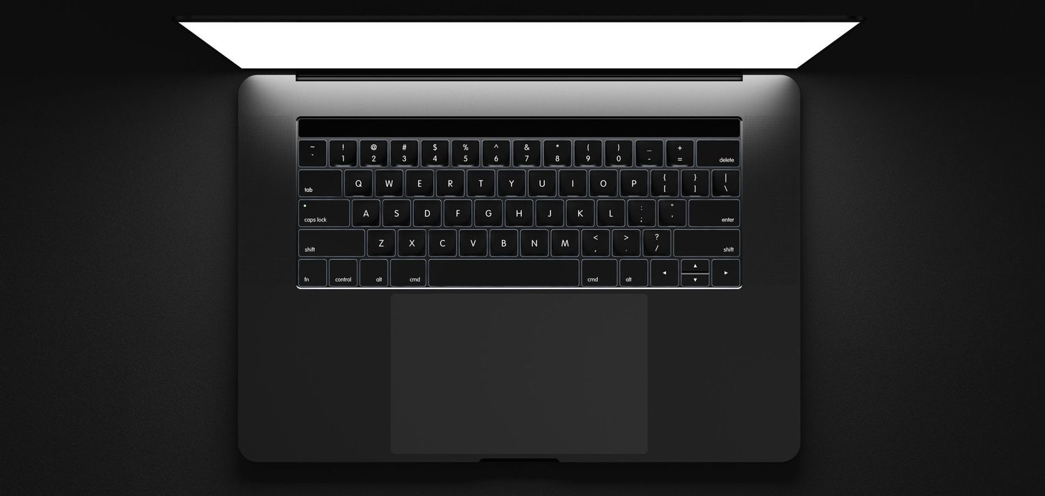 MacBook Pro keyboard with backlit keys in dark environment.