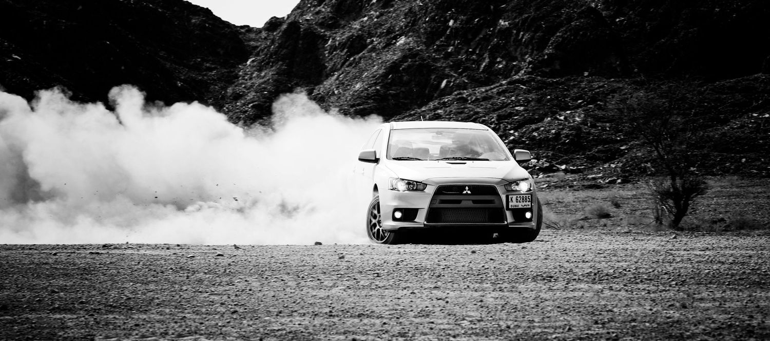 Sports cars creating dramatic dust clouds while driving on desert terrain in black and white. car photography in ontario