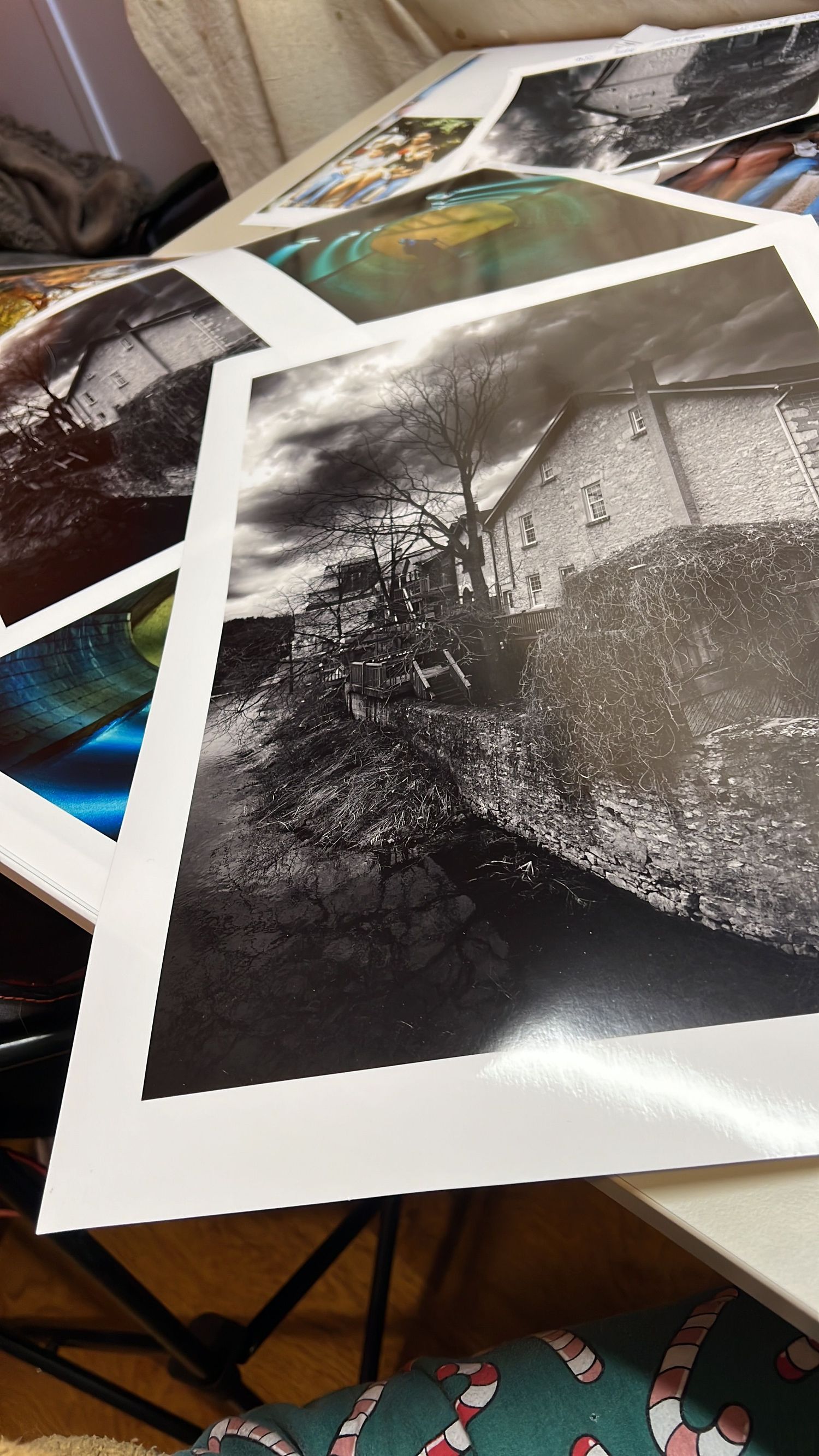 Collection of black and white landscape photographs spread out on a wooden table.
