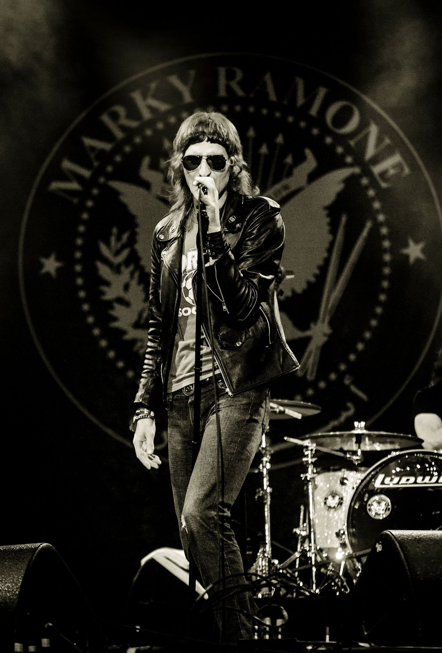 Rock band performing on stage with vintage-style black and white photography and circular logo backdrop. event photographer guelph ontario