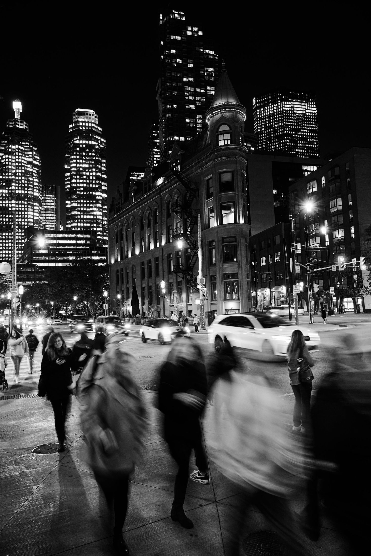 Long exposure cityscape showing blurred pedestrians against illuminated buildings at night. Commercial Photographer in Guelph and surroundin