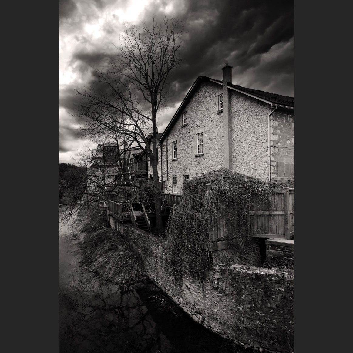 Dramatic black and white photographs of old stone buildings under moody skies.