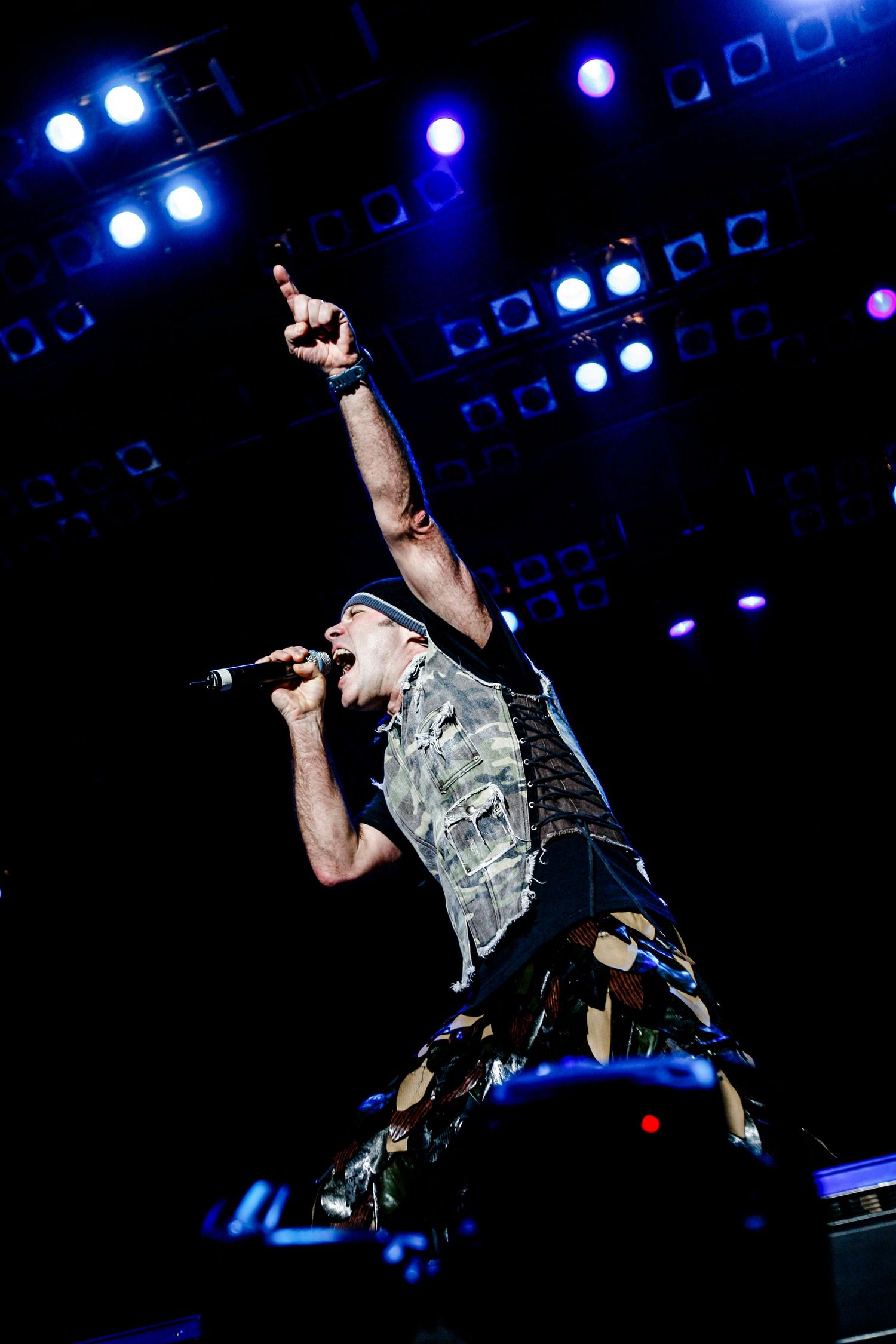 Rock performer singing passionately on stage with dramatic blue concert lighting in the background.Event photographer in Ontario Canada