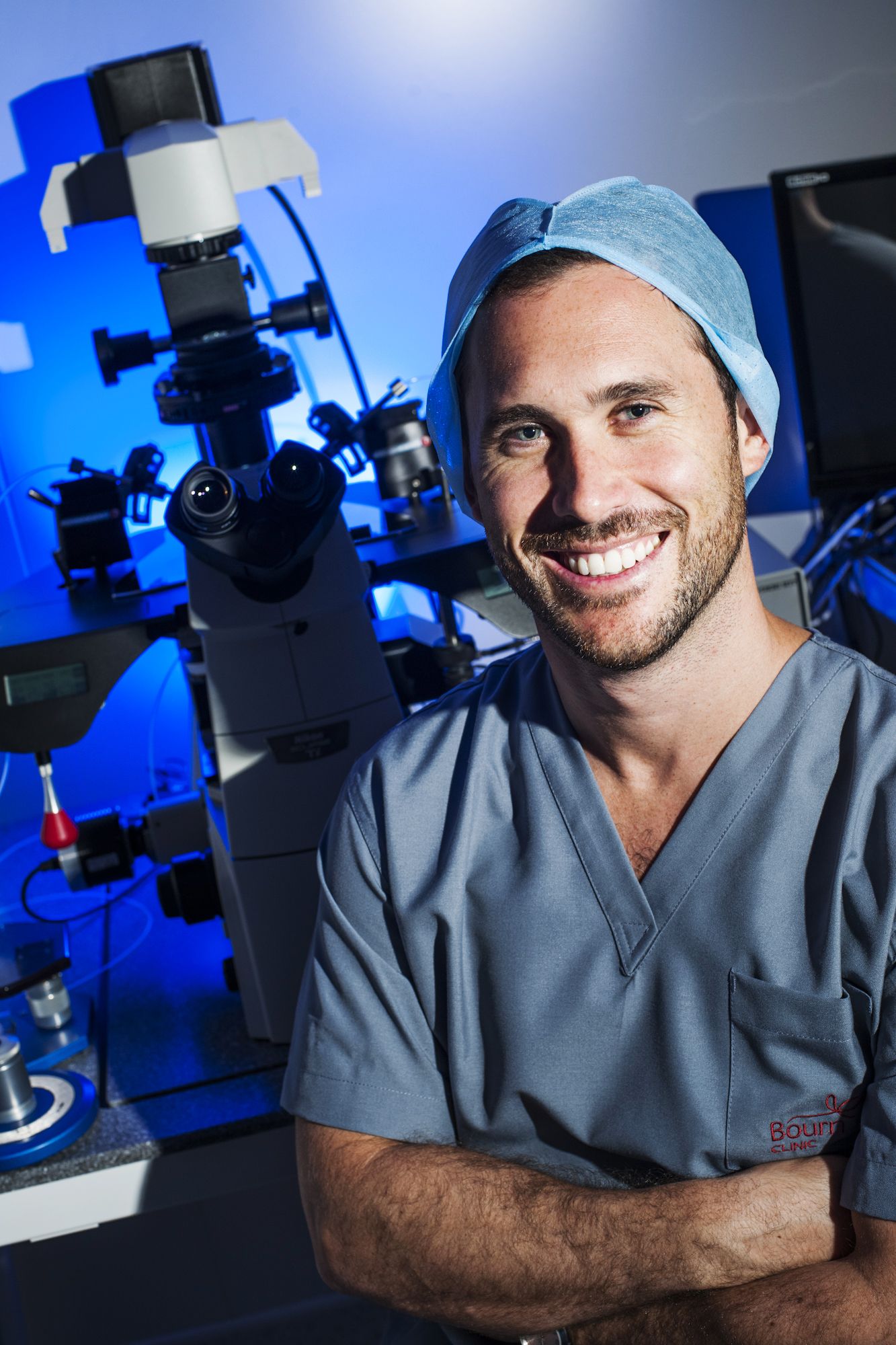 Medical professional in scrubs smiling in laboratory setting with microscopes. Commercial Photographer in Guelph Ontario