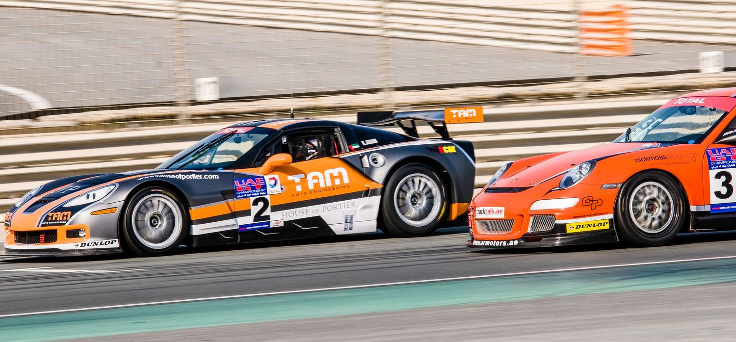 Racing cars competing on a track with orange and white striped curbing visible. car photography in ontario
