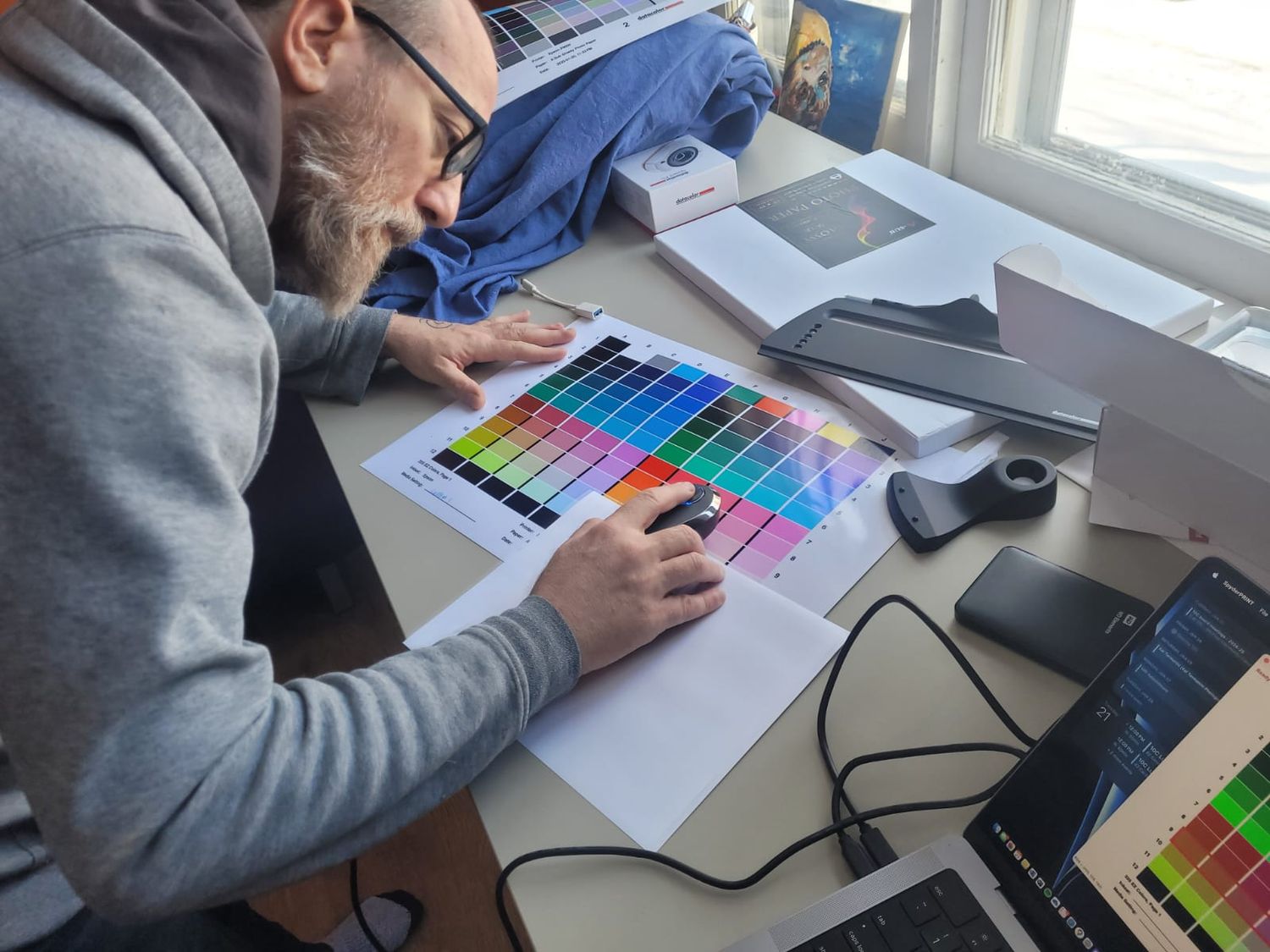 Designer working with color swatches and documents at a desk near window. Printing Services in Guelph, Kitchener, Waterloo and Cambridge
