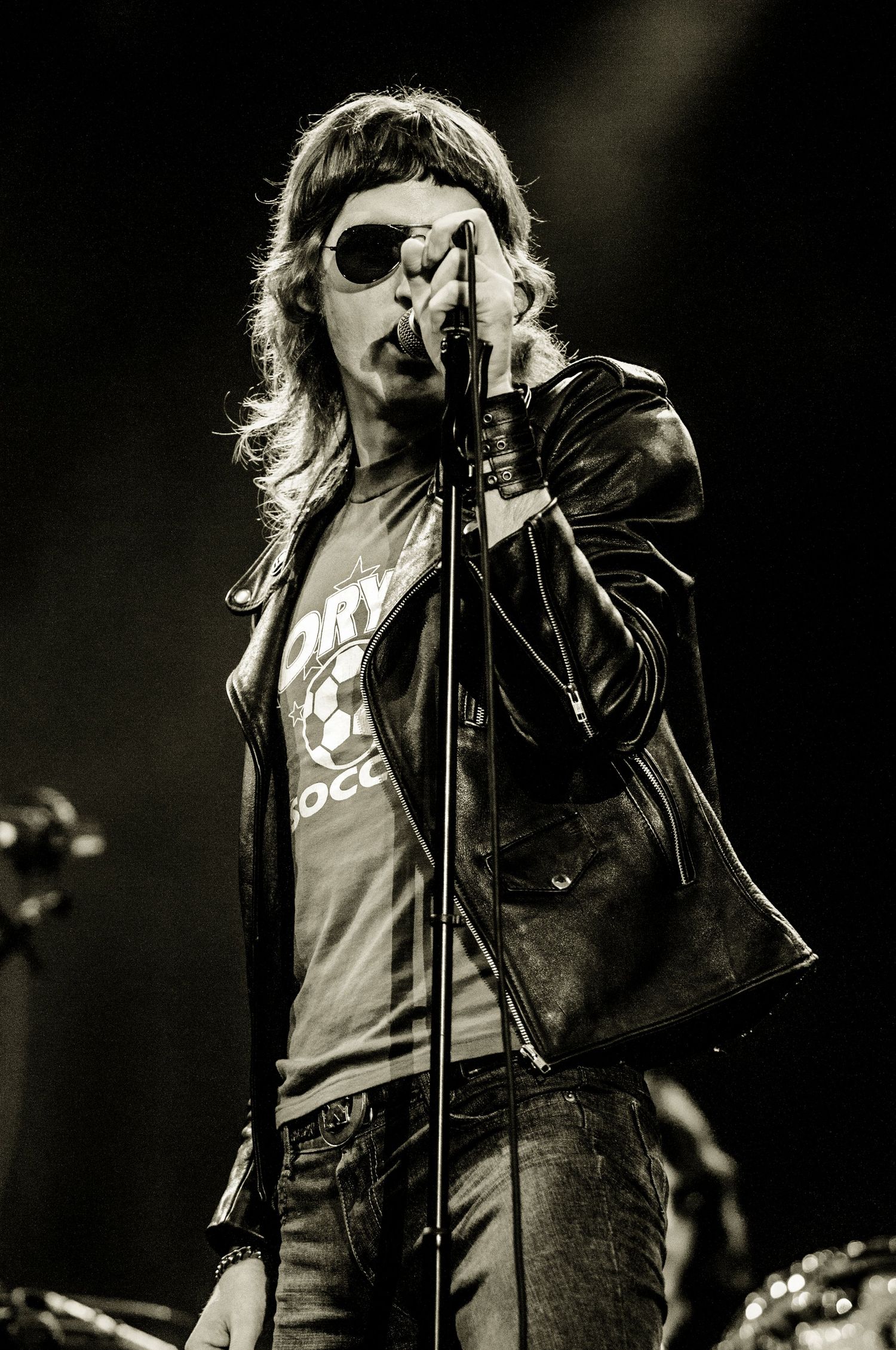 Rock vocalist in leather jacket performing on dark stage with dramatic lighting. Ramones event photographer in guelph ontario
