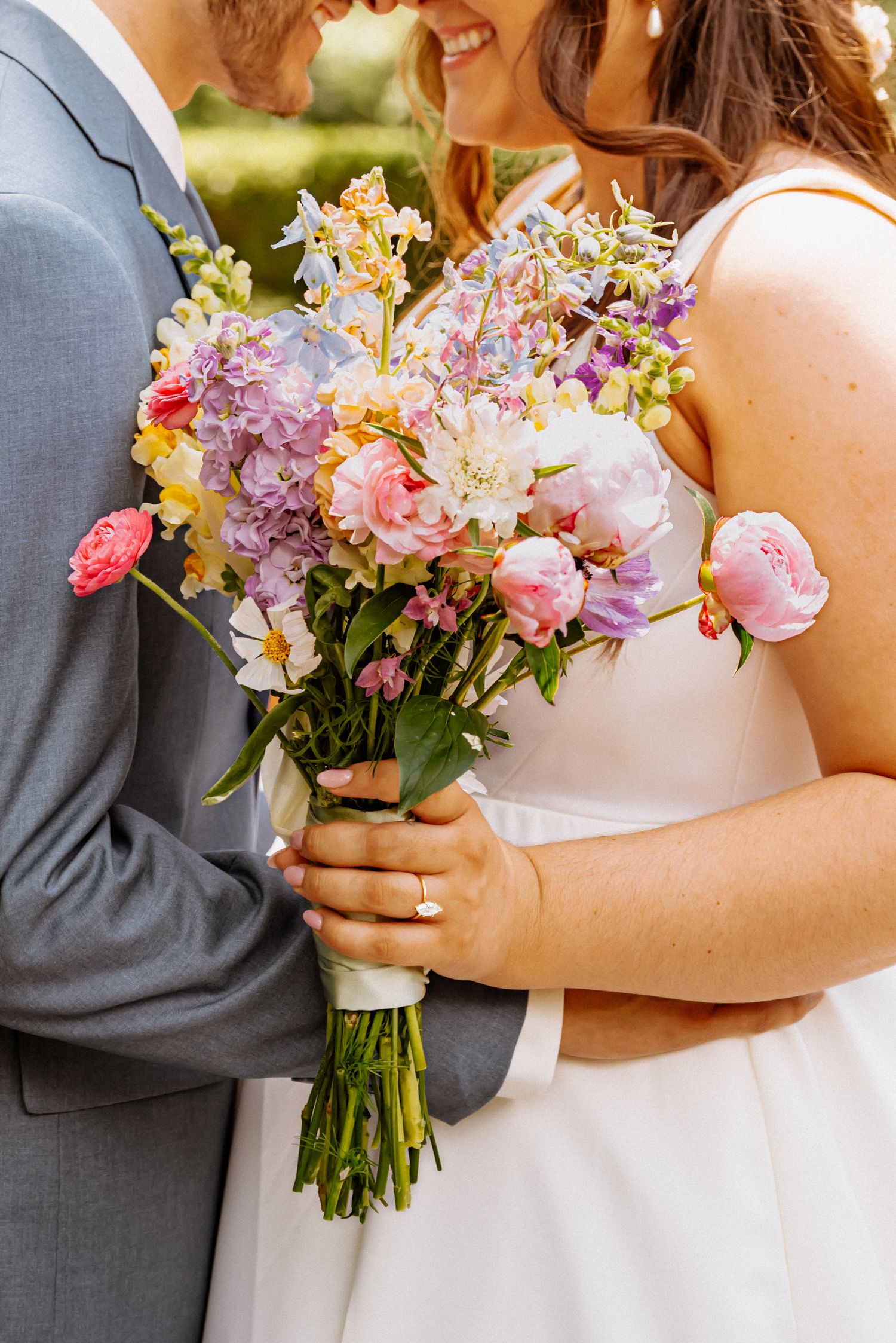 Bride and groom close up photo with the bride holding her beautiful wedding flowers while outside.