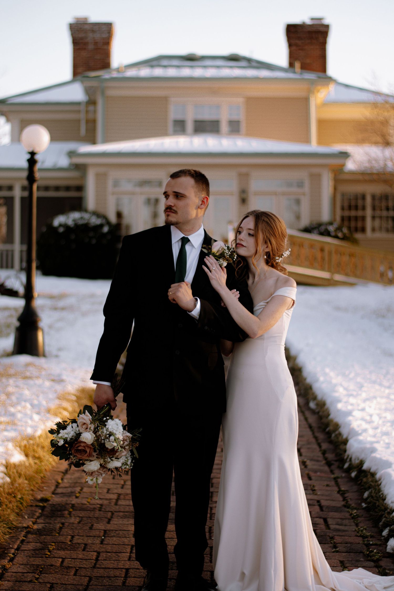 Bride and groom standing posing for a bridal portrait on a beautiful plantation, surrounded by snow.