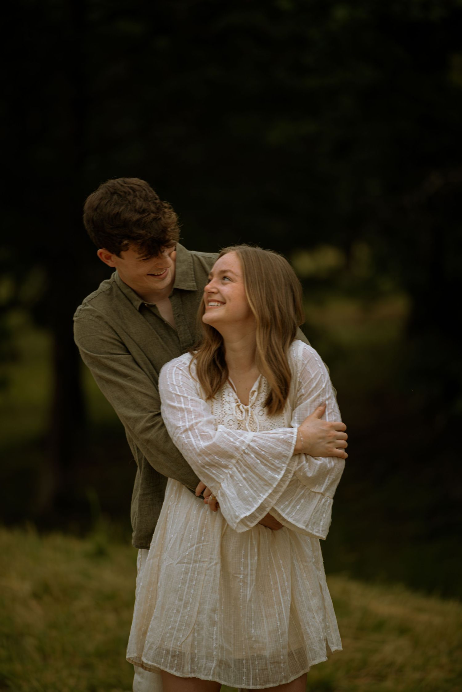Couple posing for a photo while they smile at each others embrace in front of a beautiful view.