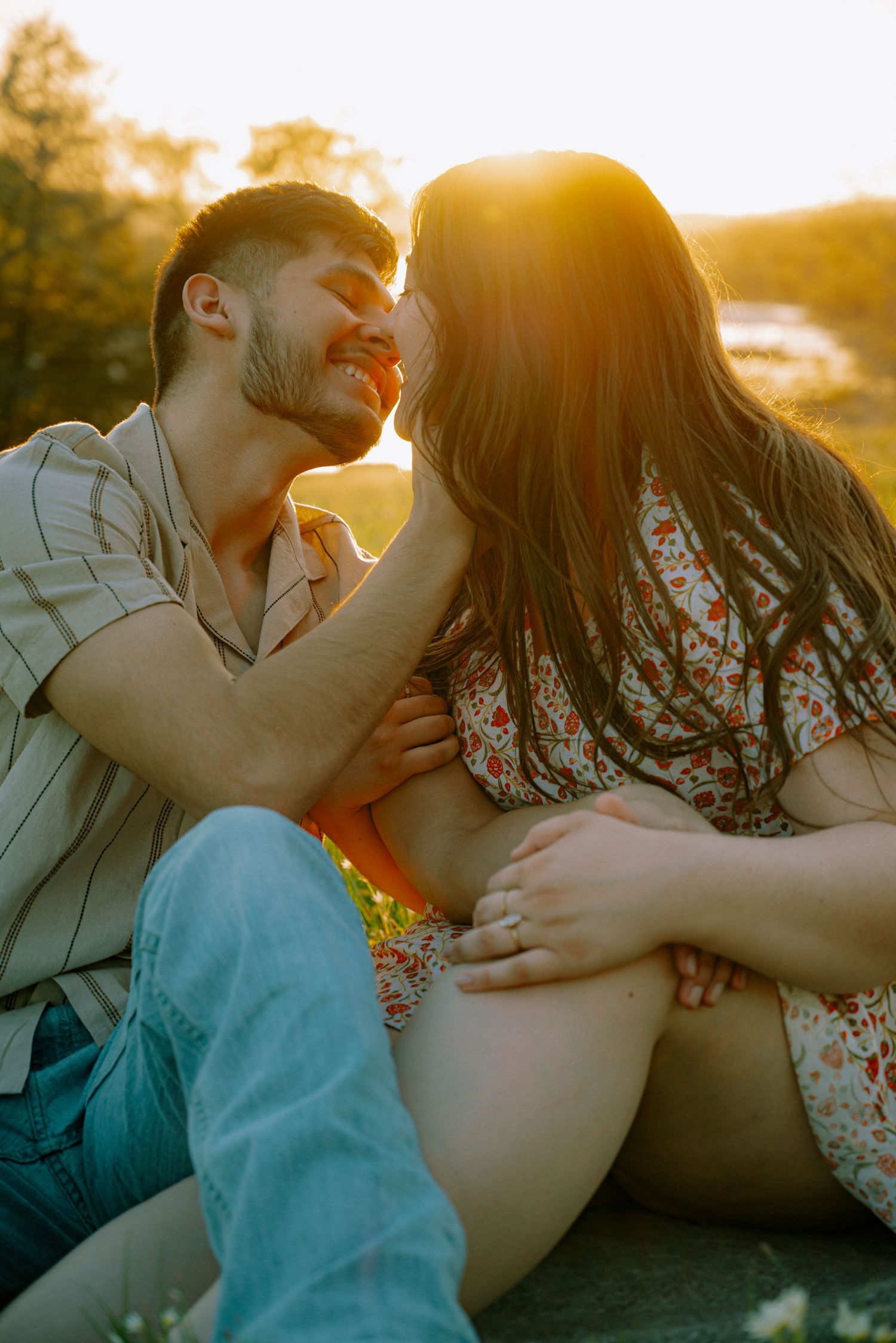 Couple sharing a romantic moment at golden hour sunset, sitting close together outdoors.