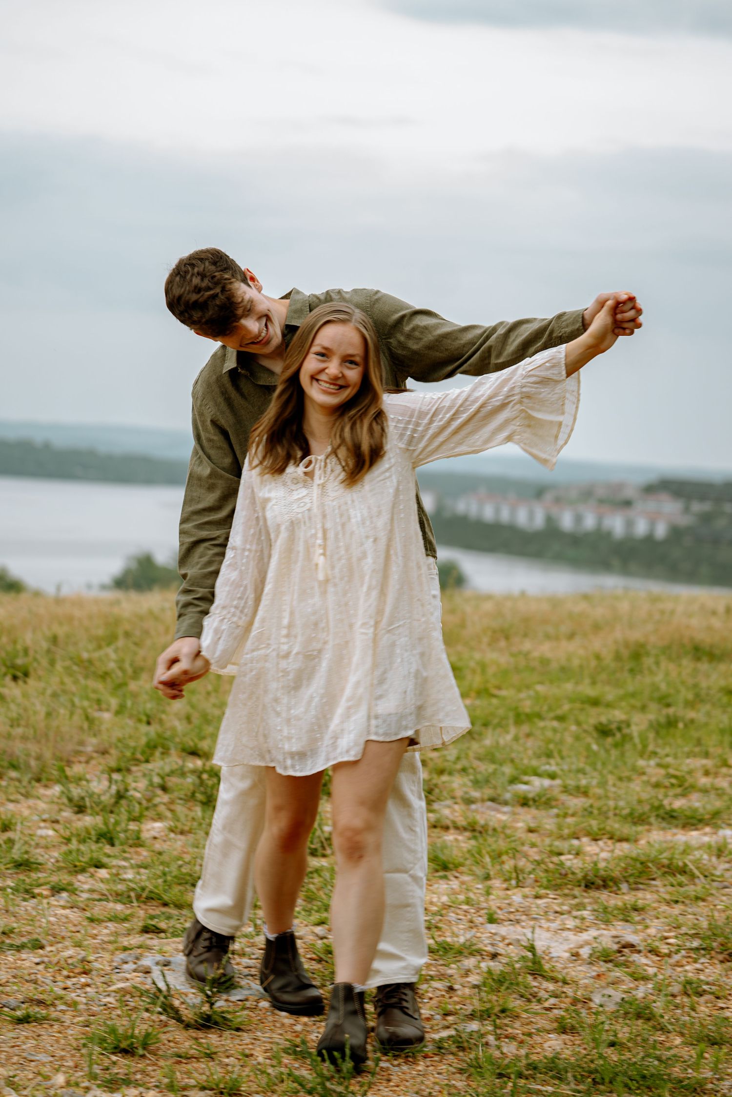 Couple posing for a photo while they hold hands and walk in front of a beautiful view.