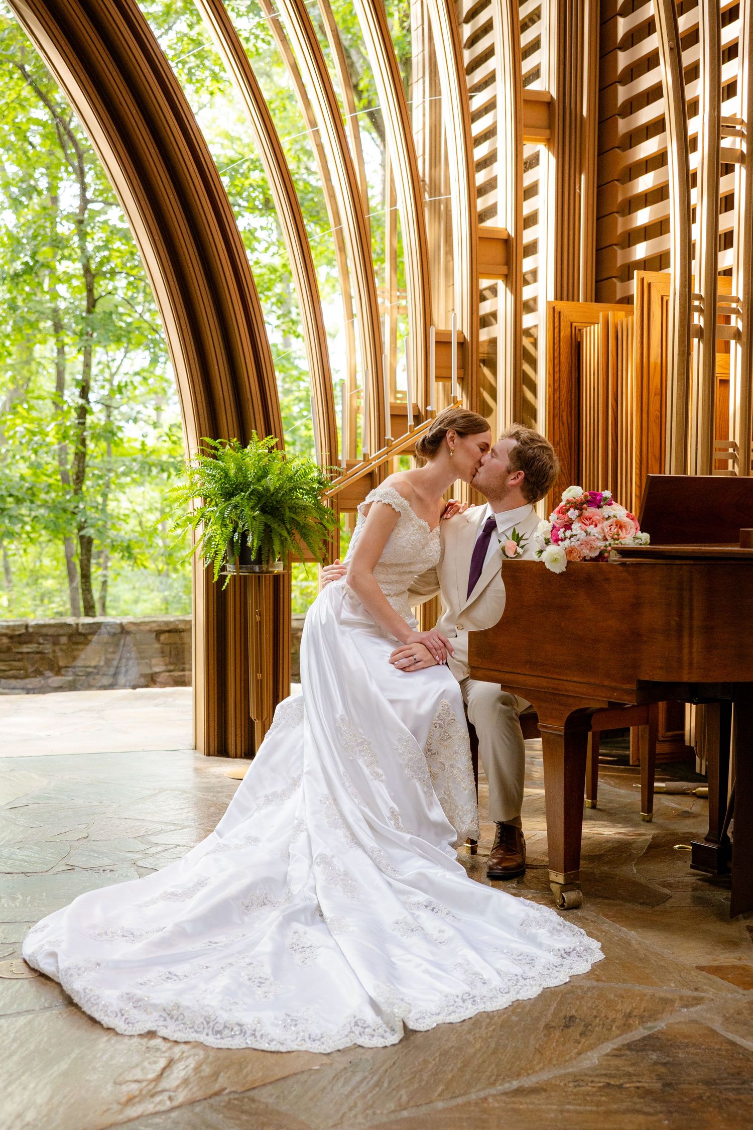 Bride and groom share a kiss beside a grand piano in The Mildred B. Memorial Chapel of Belle Vista Arkansas.